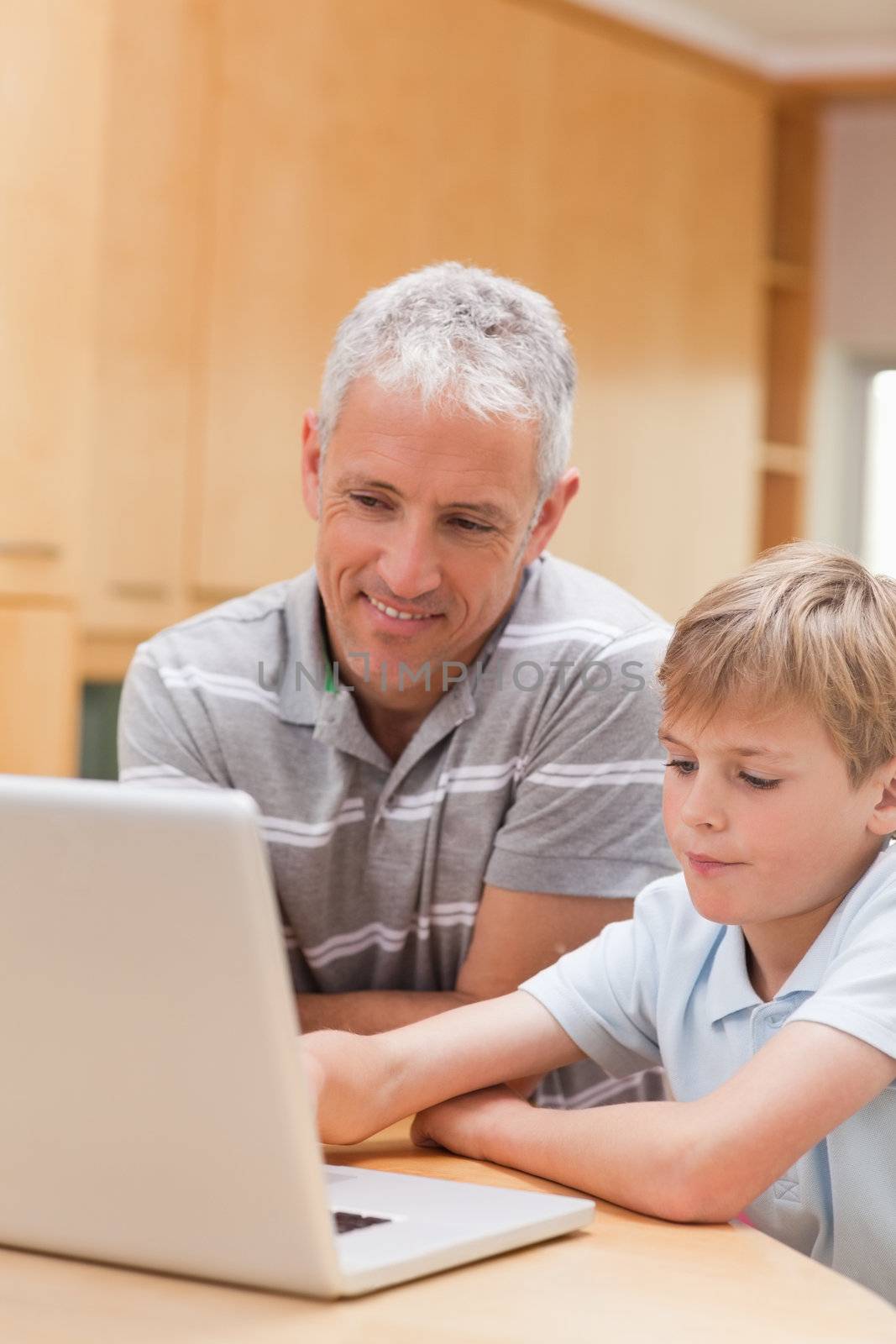 Portrait of a boy and his father using a notebook in a kitchen