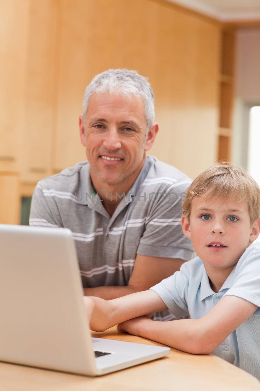 Portrait of a boy and his father using a laptop in their kitchen