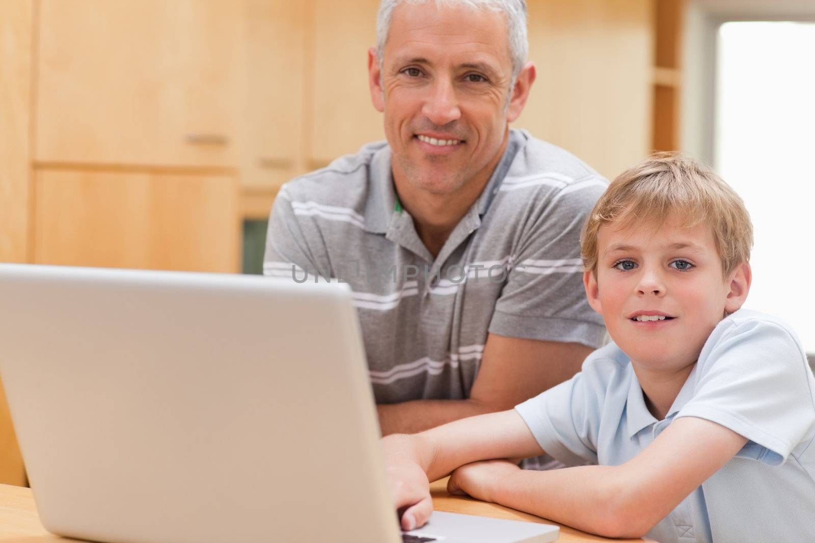 Young boy and his father using a laptop in a kitchen