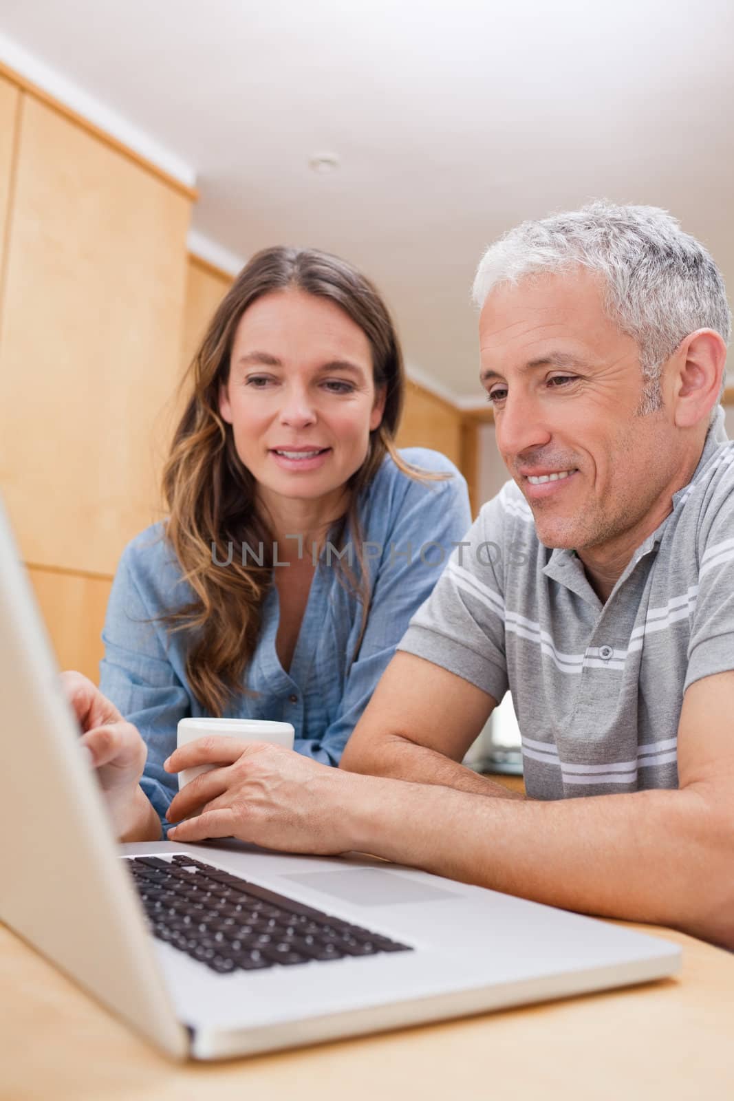 Portrait of a couple using a laptop while having coffee in their kitchen