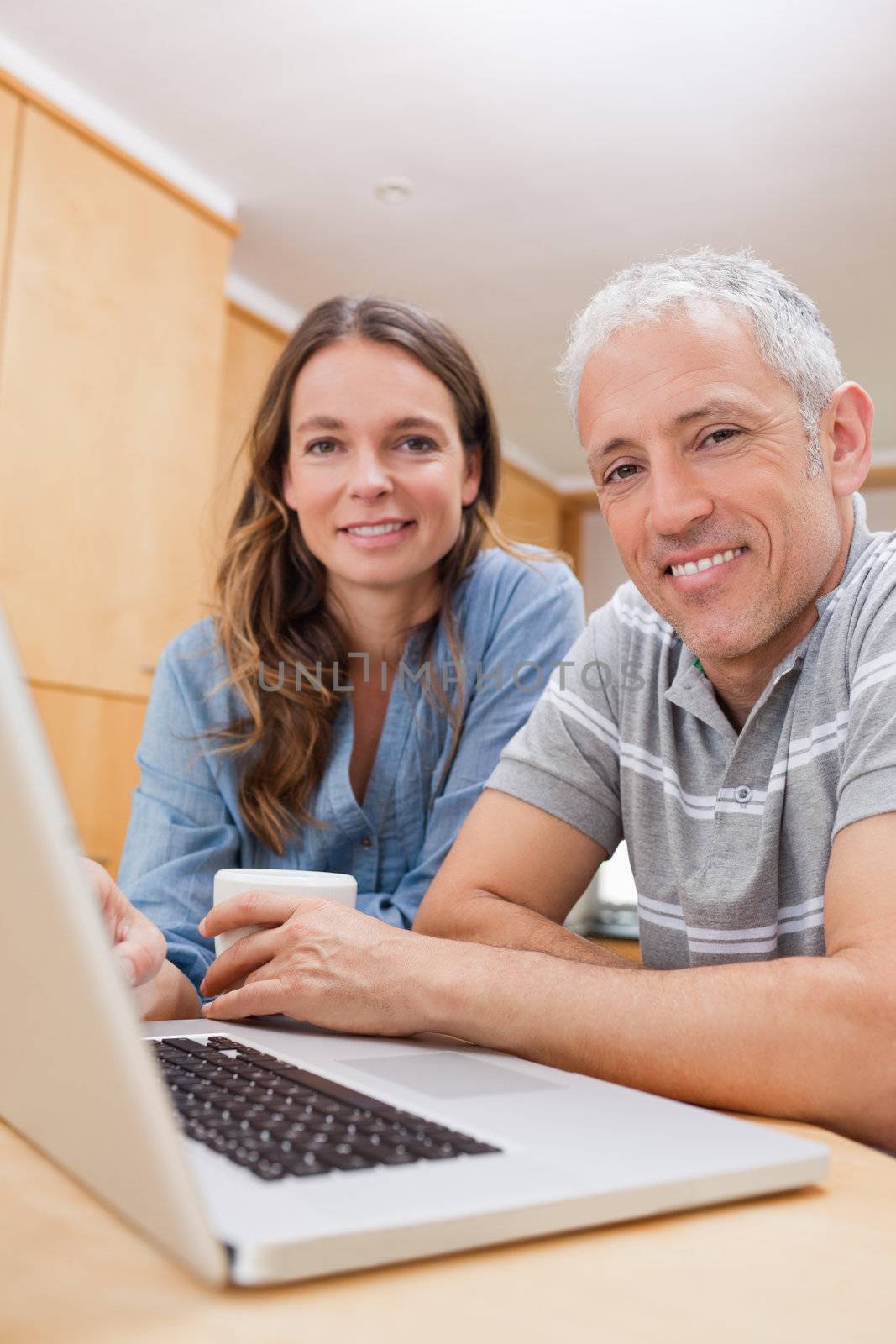 Portrait of a couple using a laptop while having tea in their kitchen