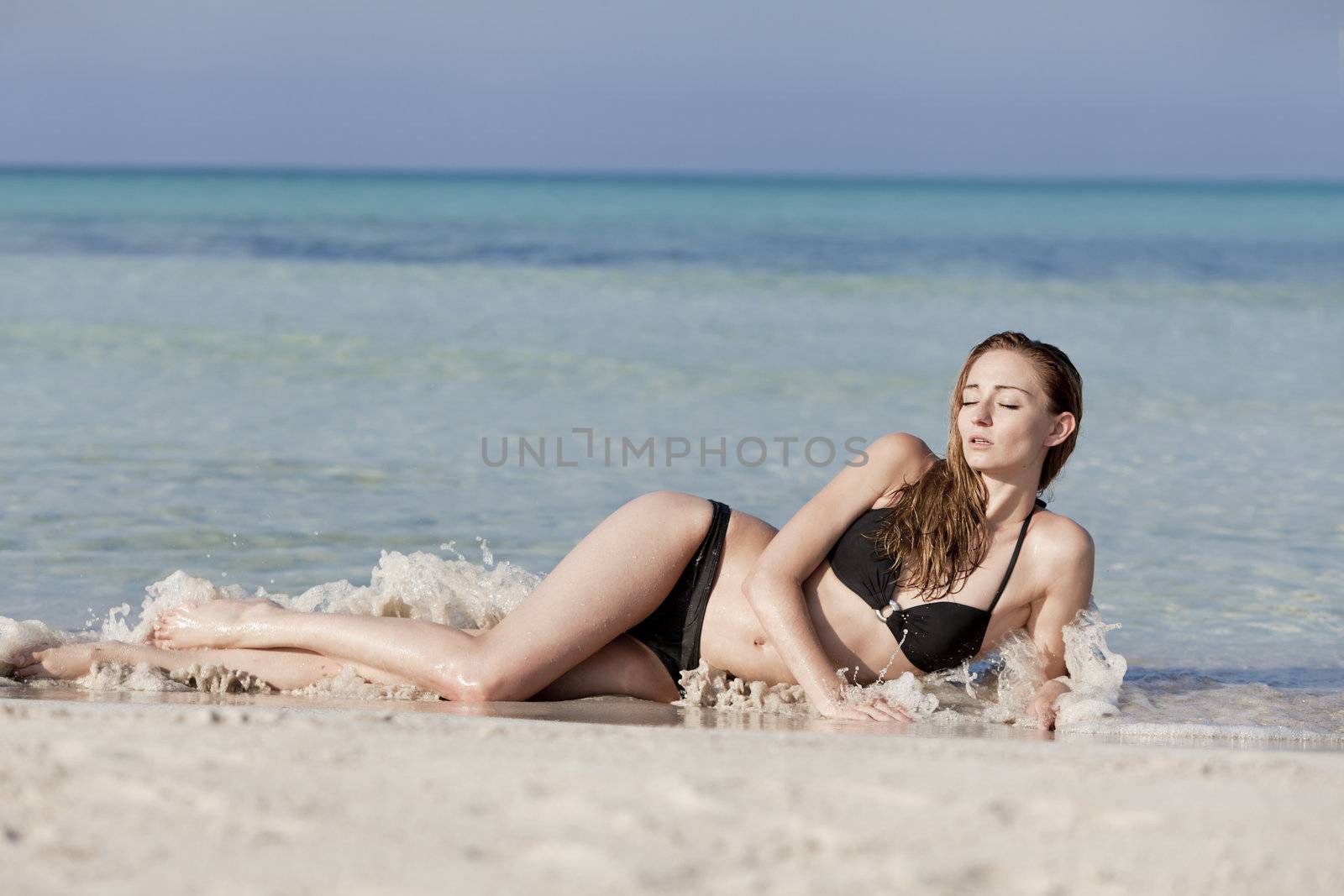 Young woman with black bikini Sexy girls on the beach in water with blue sky in summer vacation