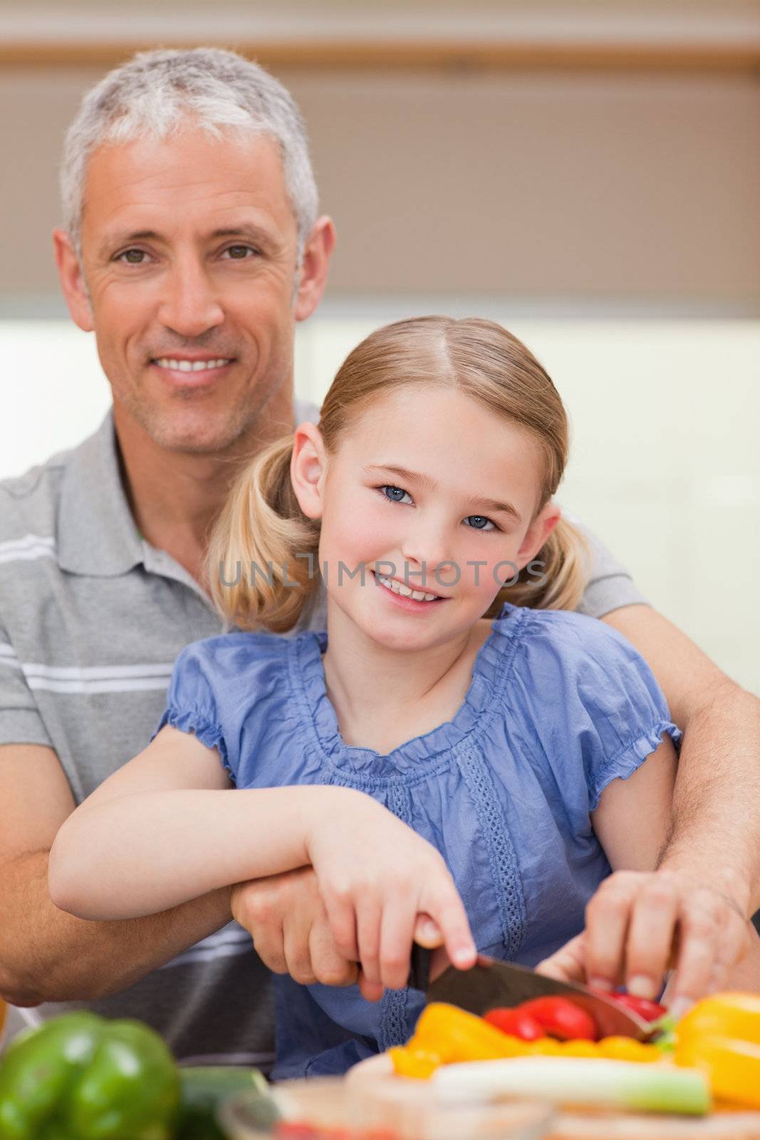 Portrait of a man slicing pepper with his daughter in a kitchen