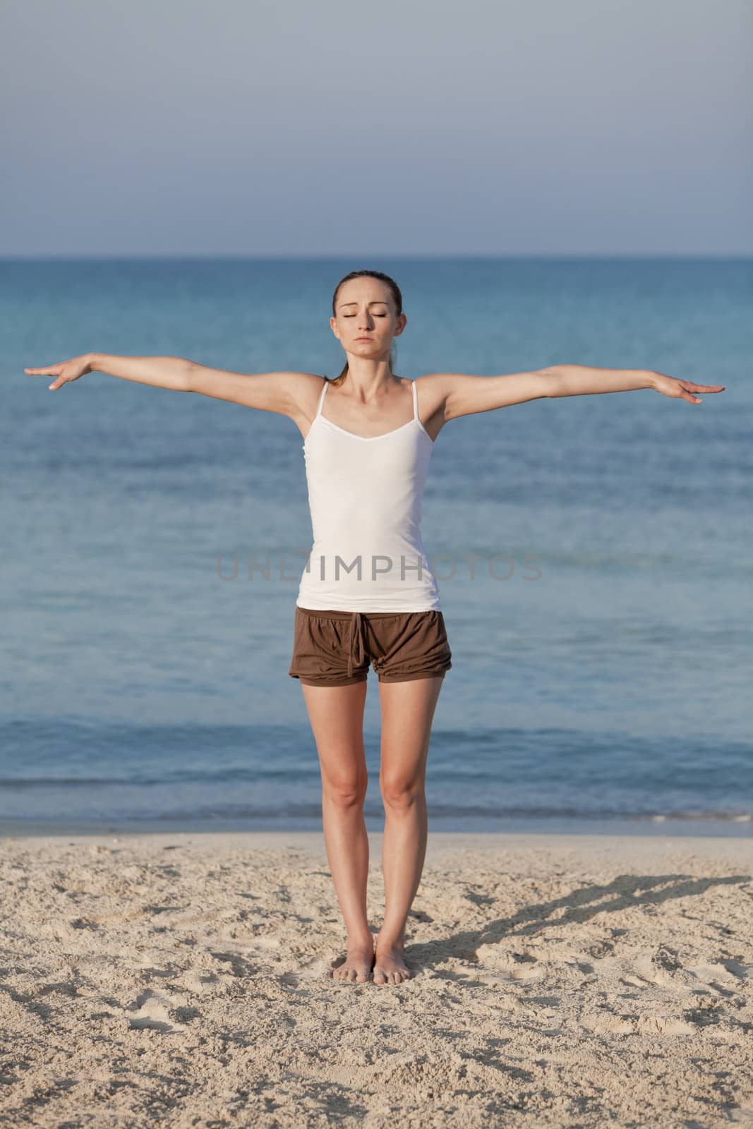 Young sporty woman doing sport yoga on the beach in the sand on the beach in the sun