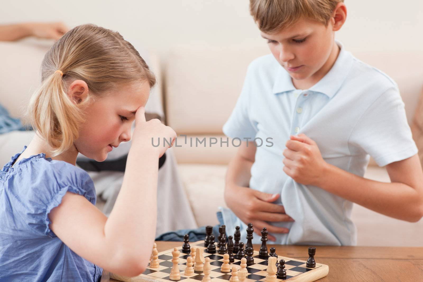 Siblings playing chess in a living room
