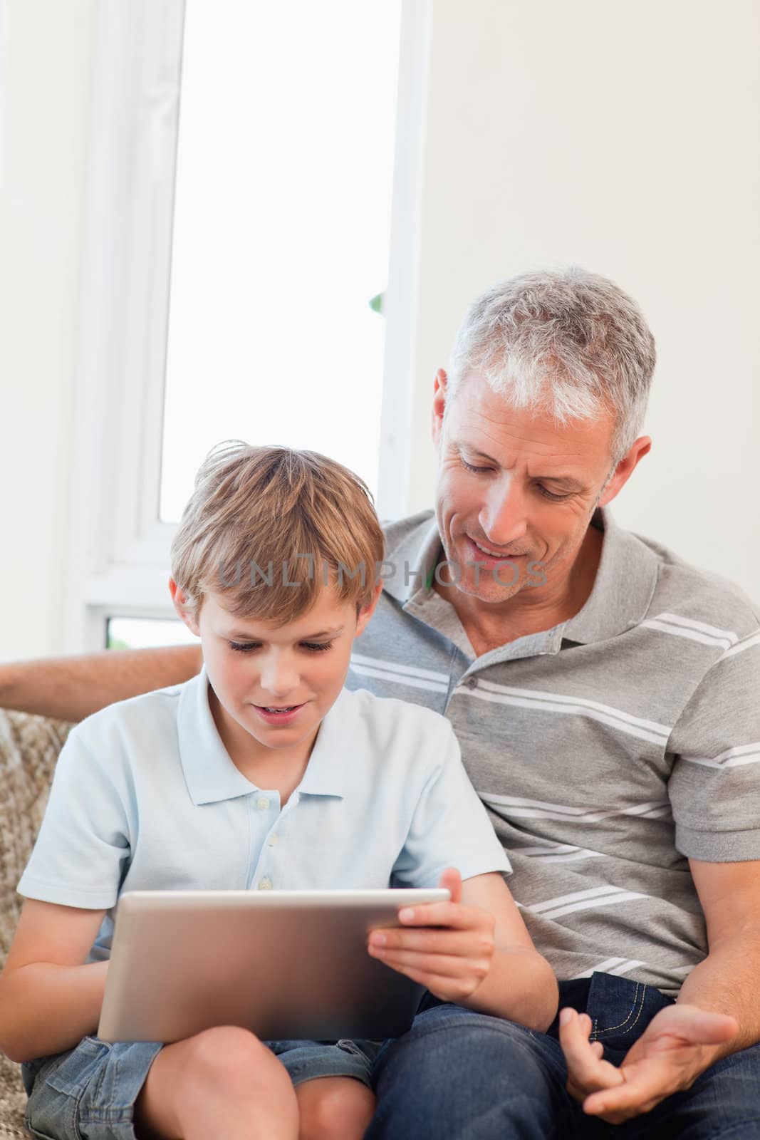 Portrait of a father and his son using a tablet computer in a living room
