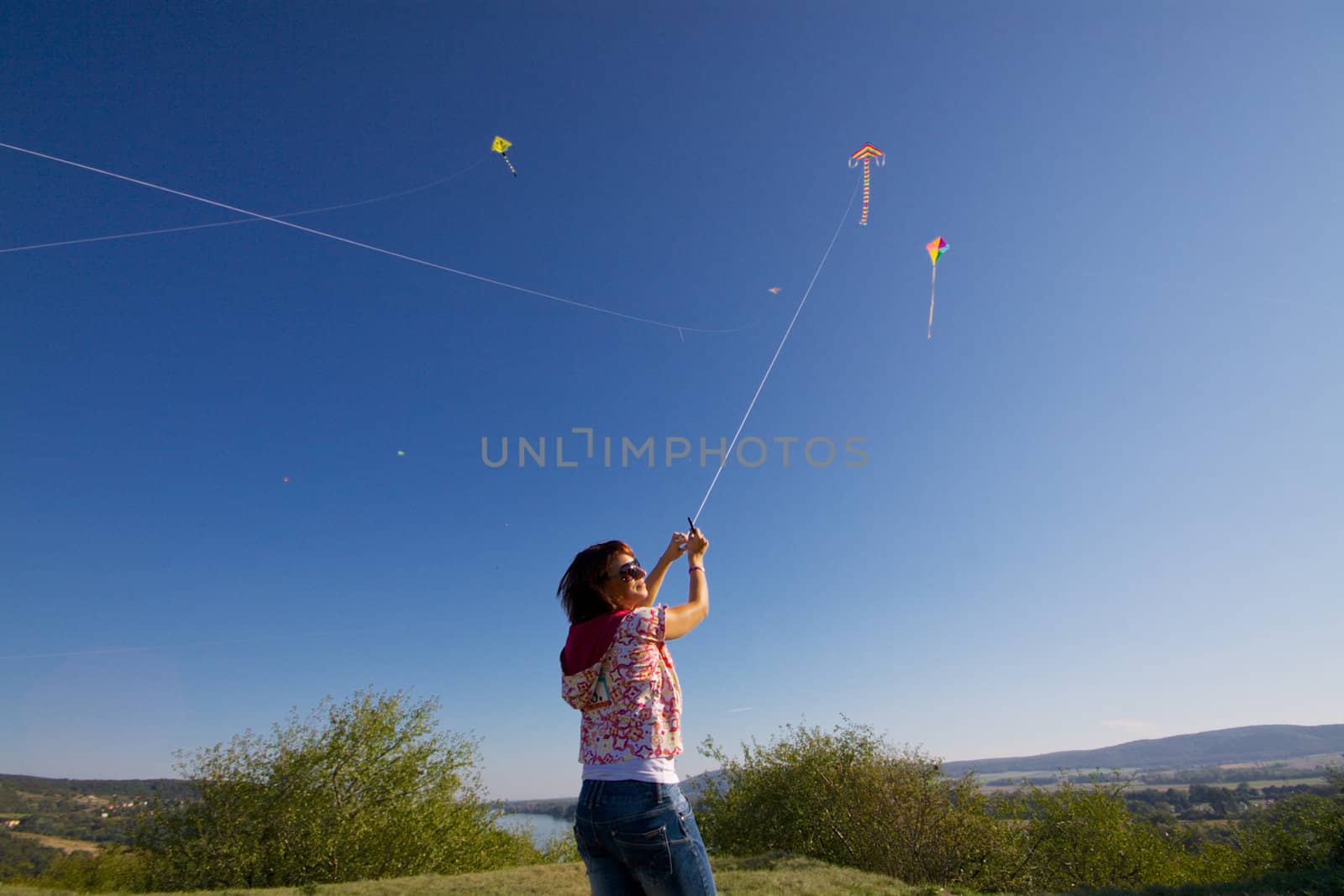Young girl playing with colorful flying kite on sunny autumn day