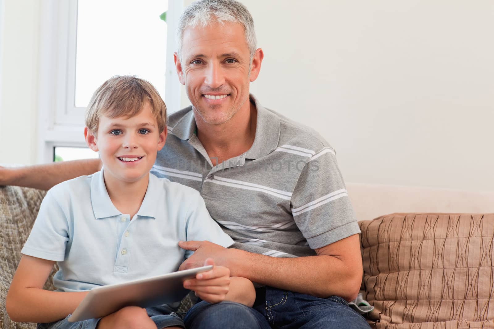 Smiling father and his son using a tablet computer in a living room
