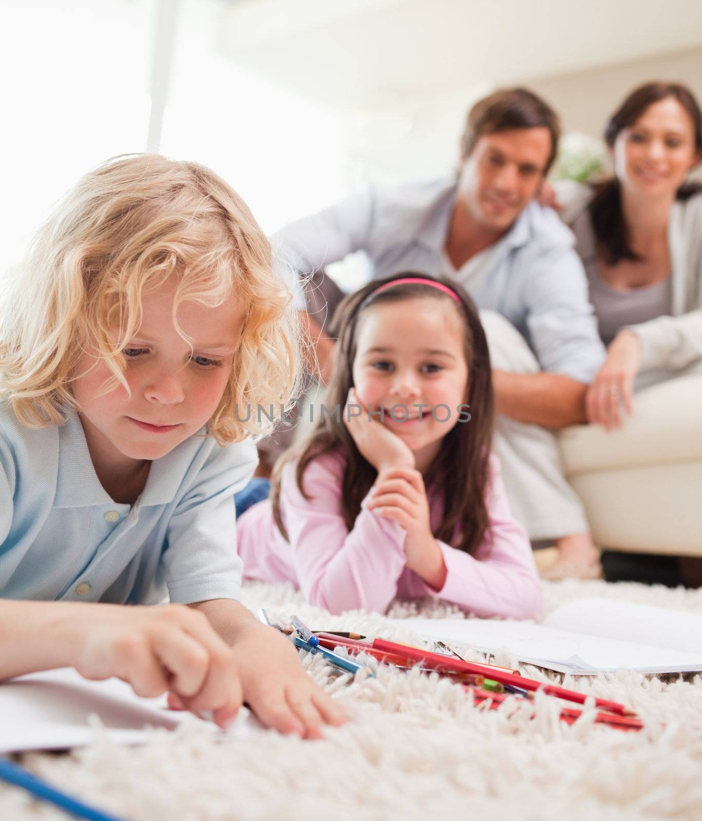 Portrait of siblings drawing while their parents are in the back by Wavebreakmedia