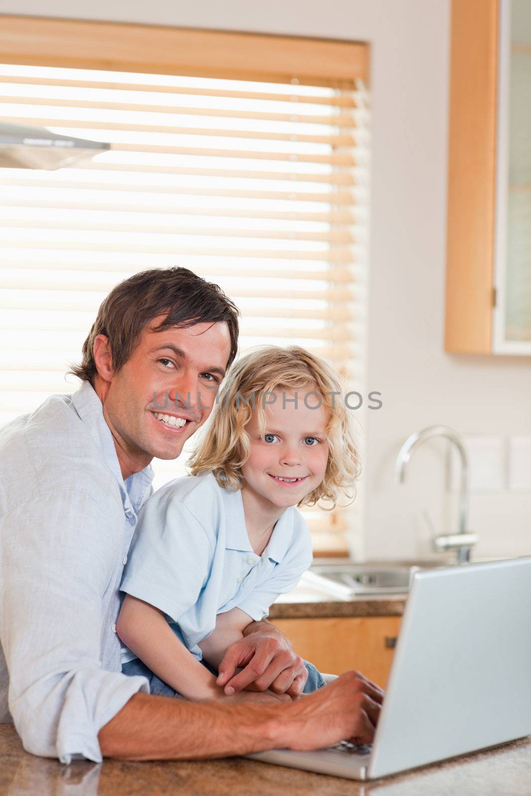 Portrait of a boy and his father using a notebook together in a kitchen
