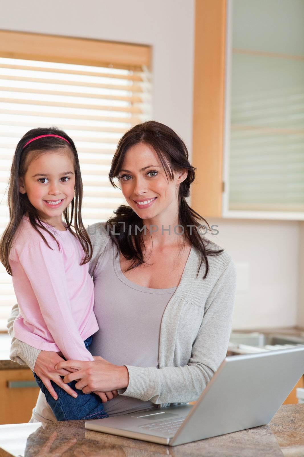Portrait of a girl and her mother using a notebook in a kitchen