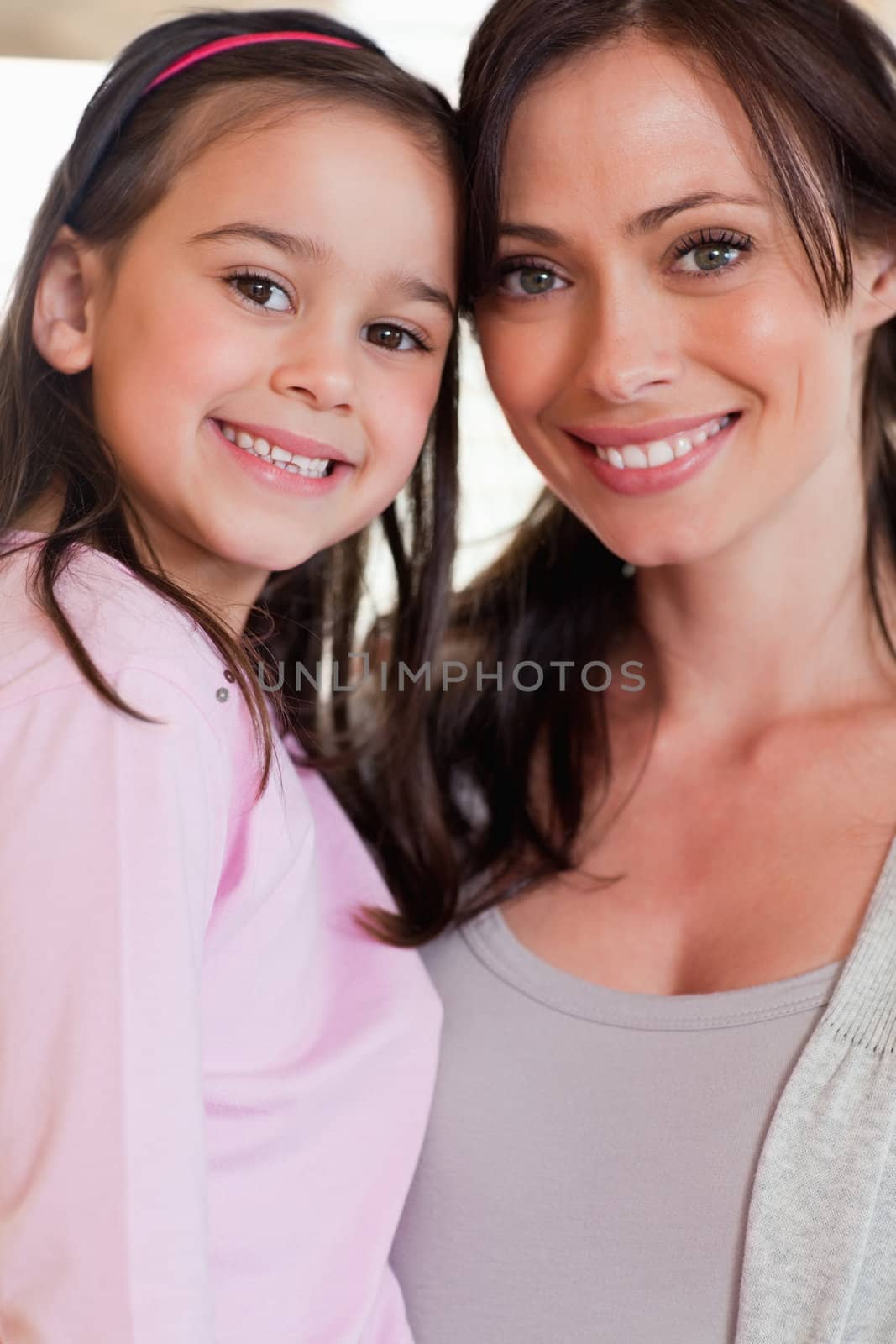 Portrait of a girl and her mother posing while smiling at the camera