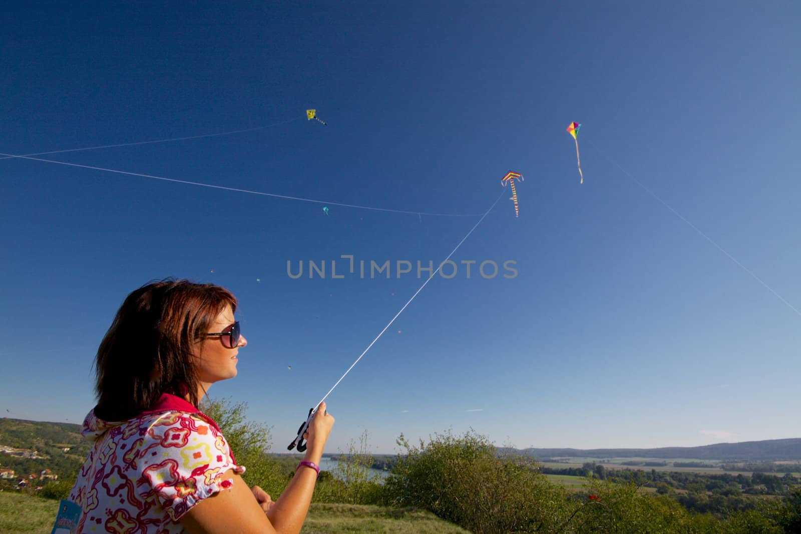 Young girl playing with colorful flying kite on sunny autumn day