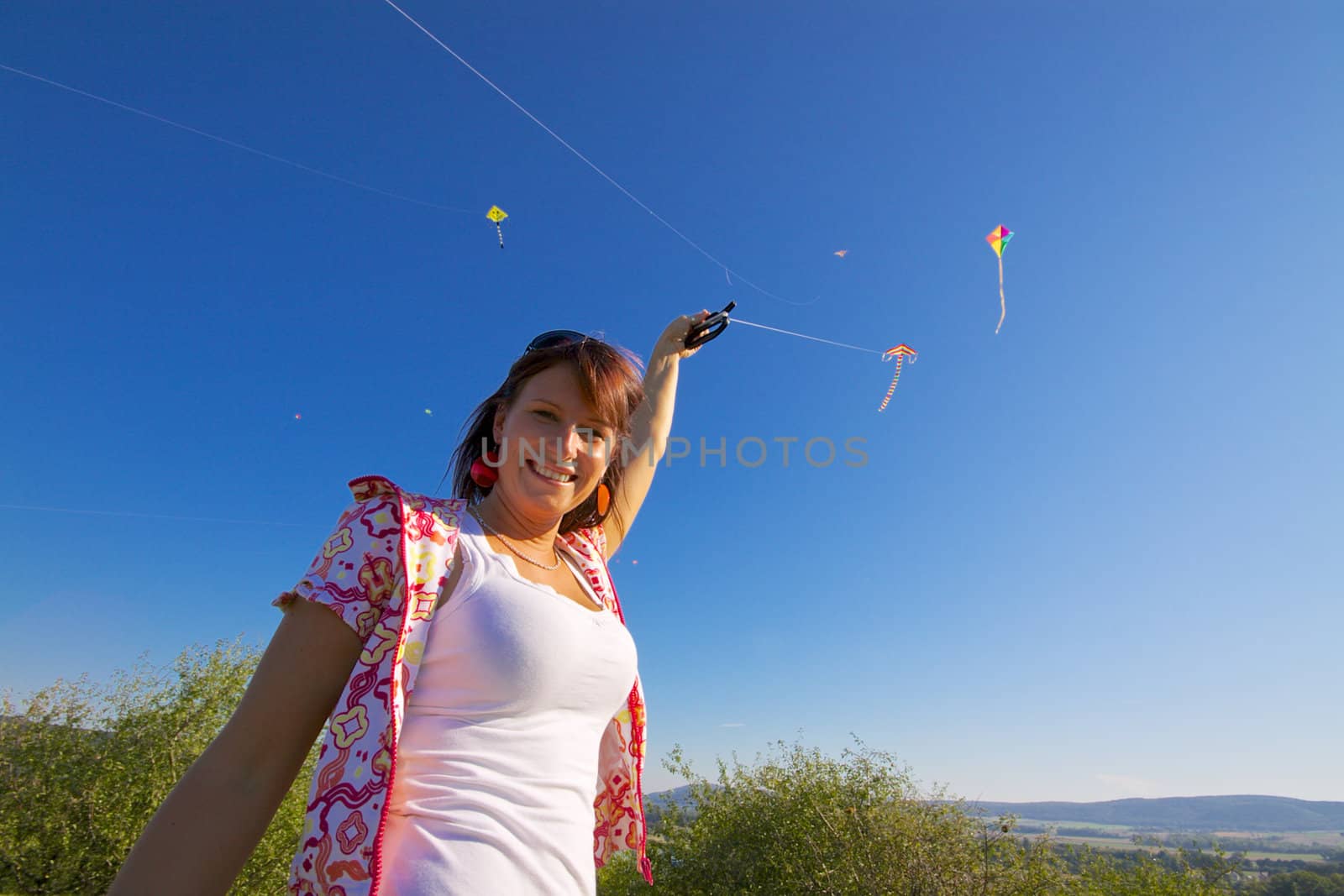 Beautiful young girl playing with colorful flying kite on sunny autumn day