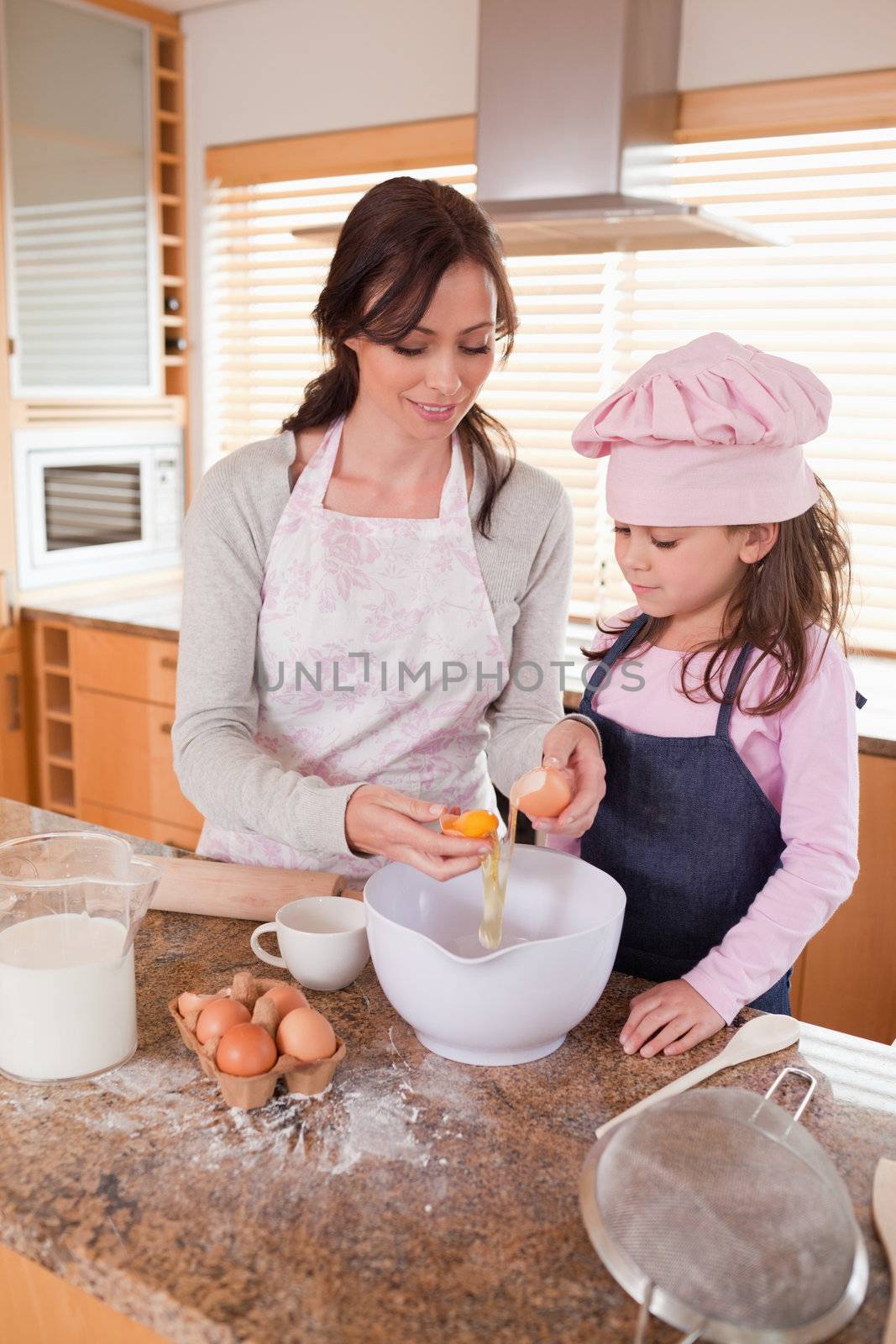 Portrait of a happy mother and her daughter baking in a kitchen