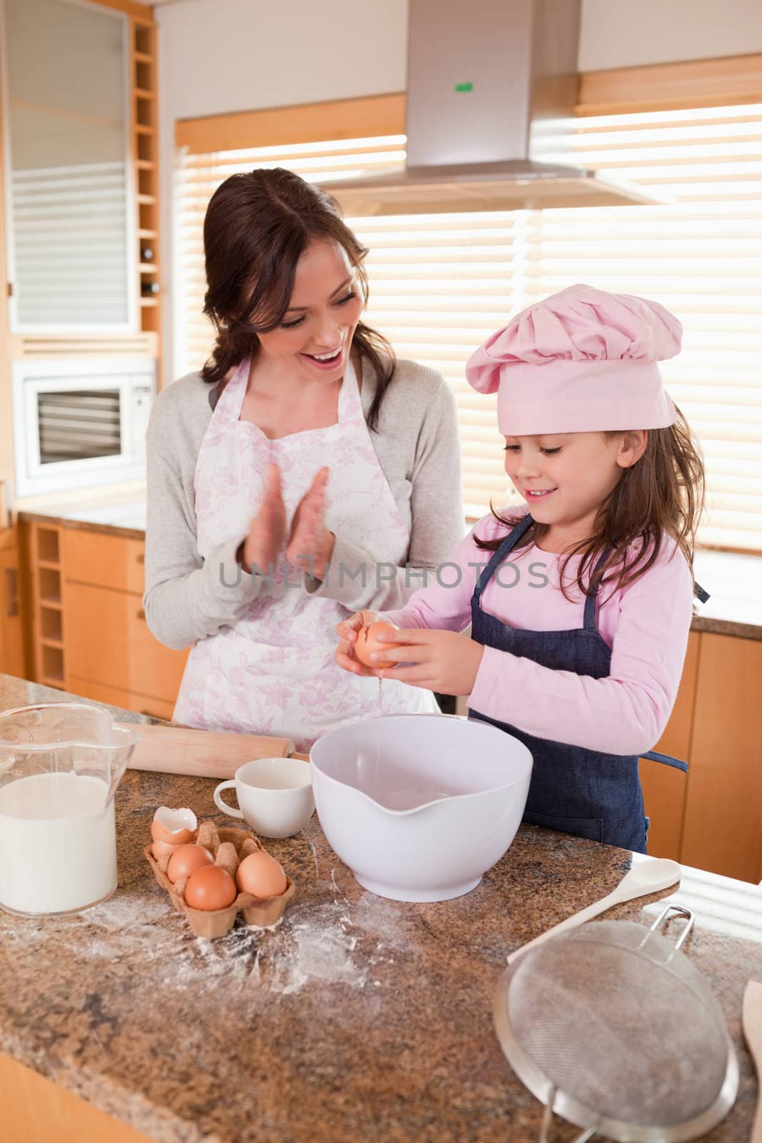 Portrait of a mother teaching her daughter how to bake in a kitchen
