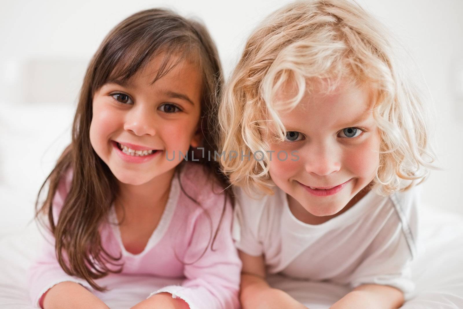 Siblings lying on their bellies in a bedroom