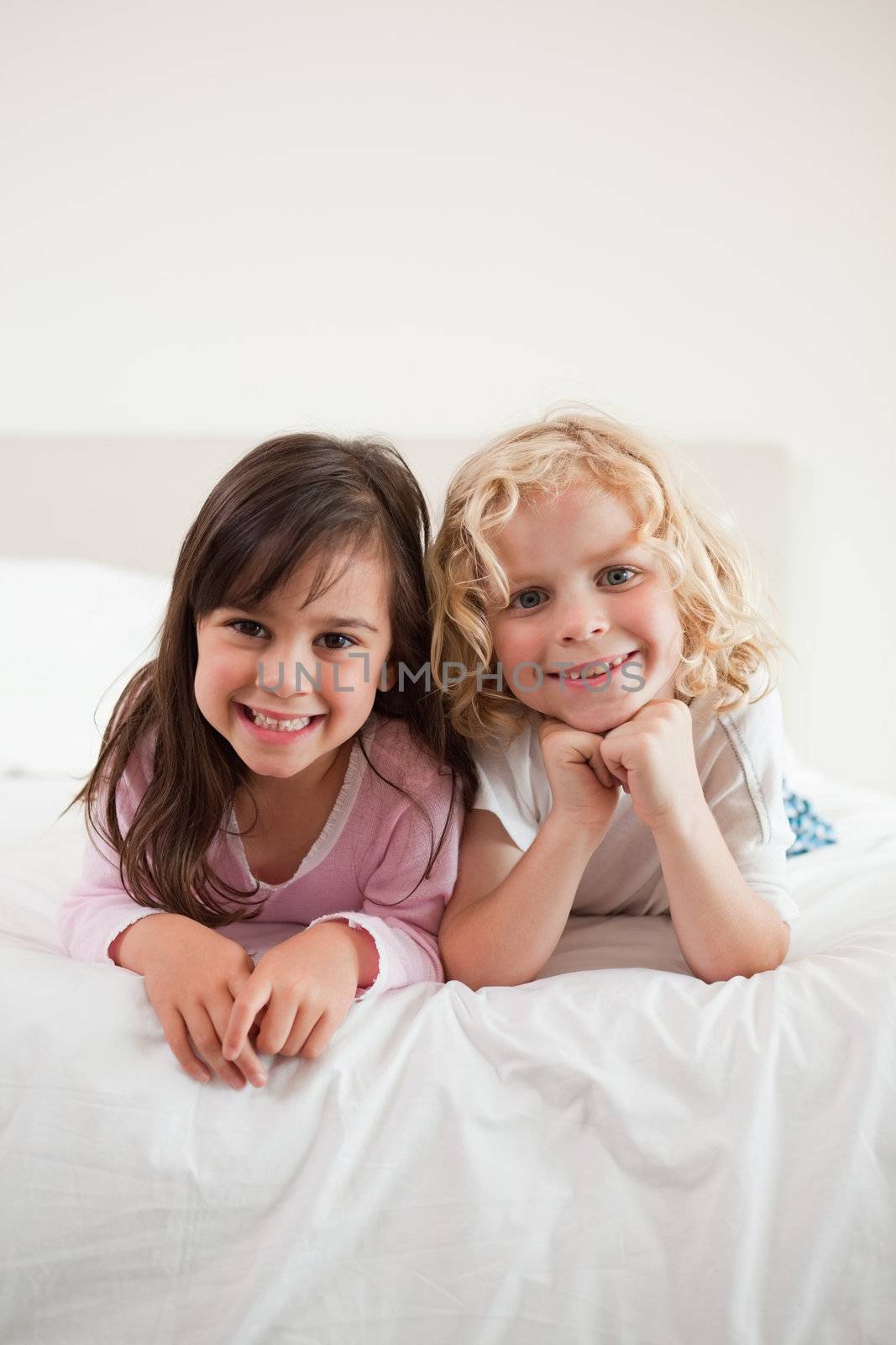 Portrait of children lying on their bellies in a bedroom