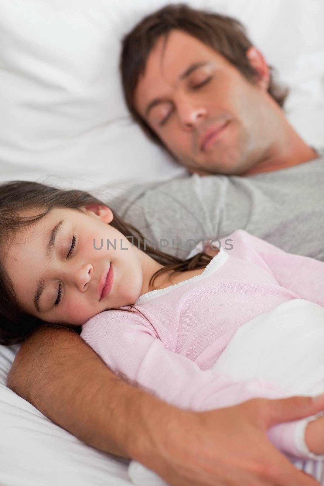 Portrait of a father sleeping with his daughter in a bedroom