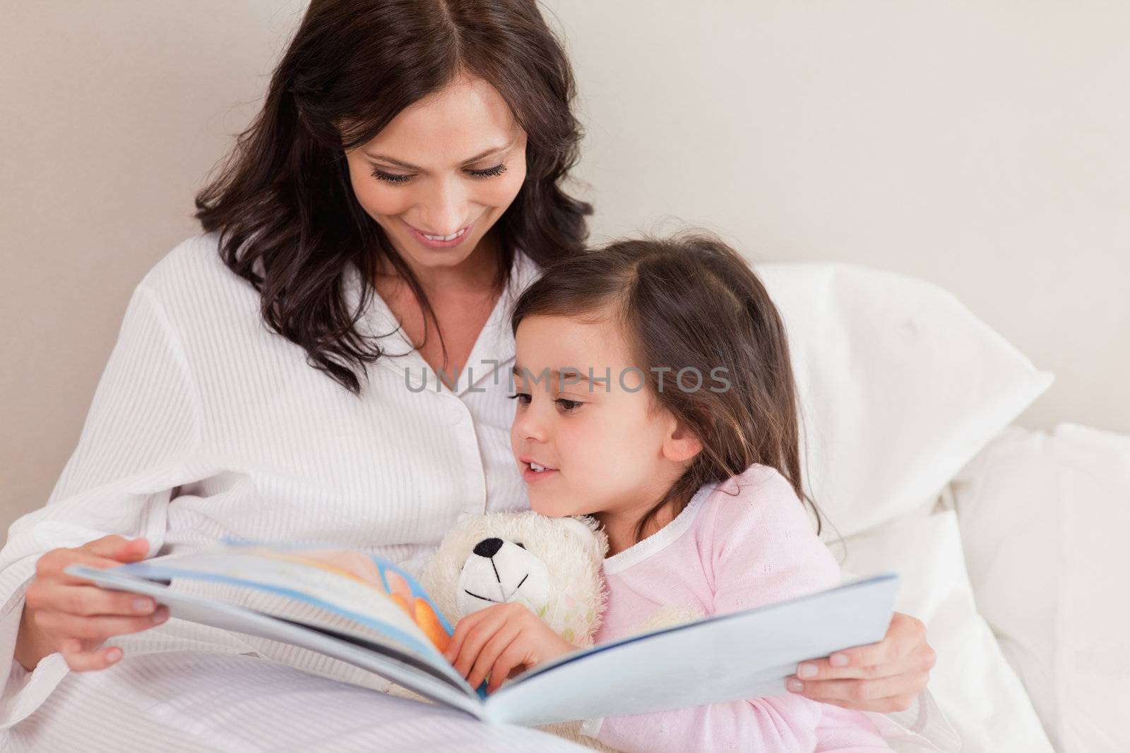 Mother reading a story to her daughter in a bedroom