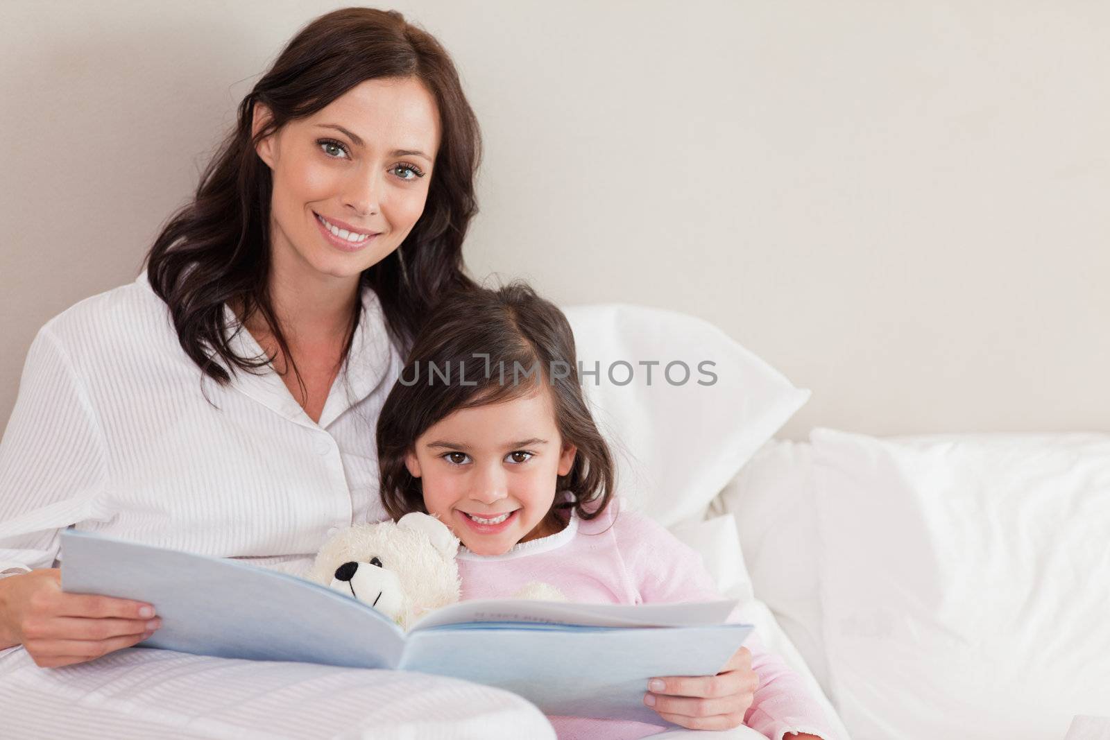 Happy mother reading a story to her daughter in a bedroom