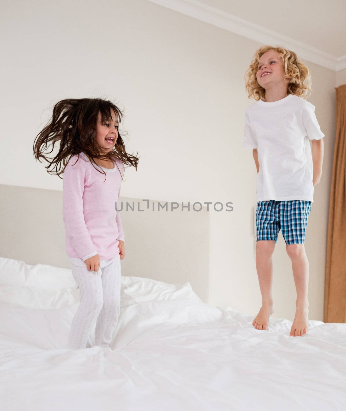 Portrait of children jumping on a bed 