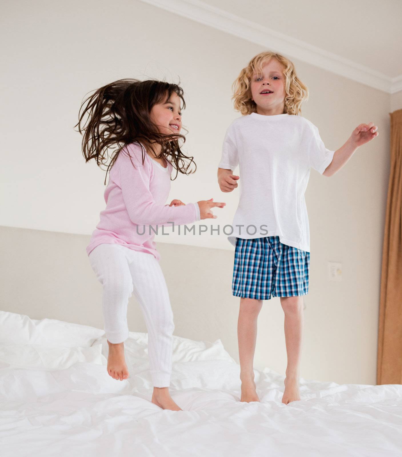 Portrait of siblings jumping on a bed