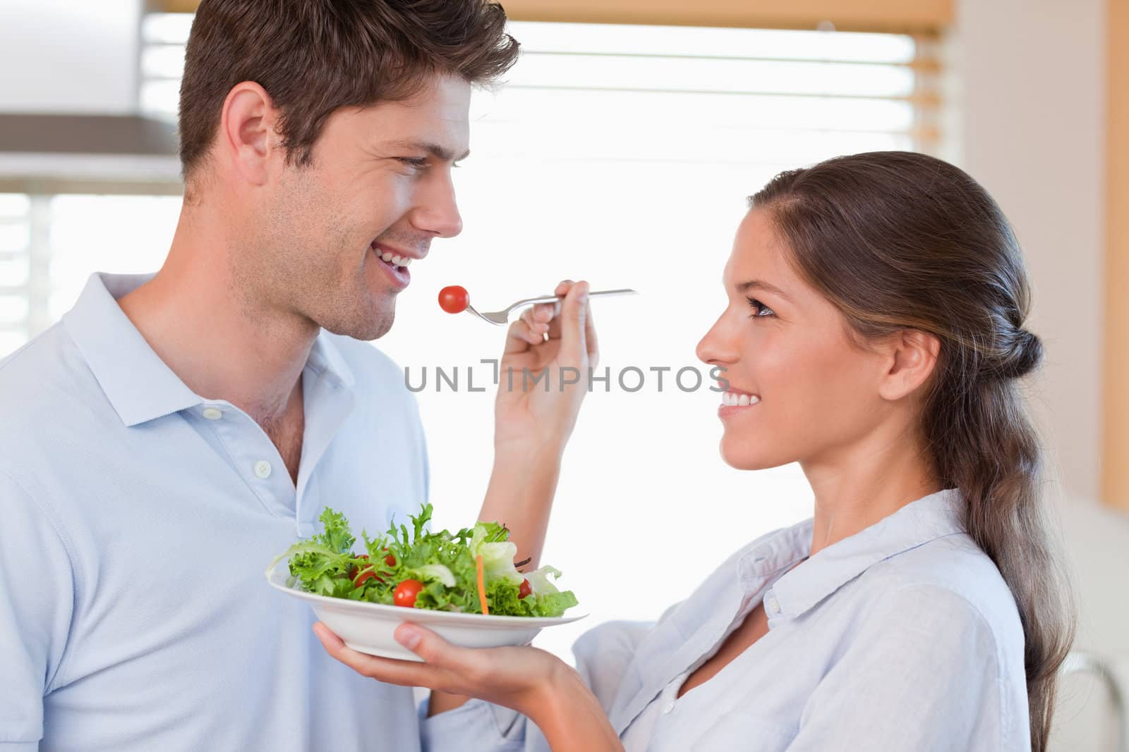 Woman feeding her husband in their kitchen
