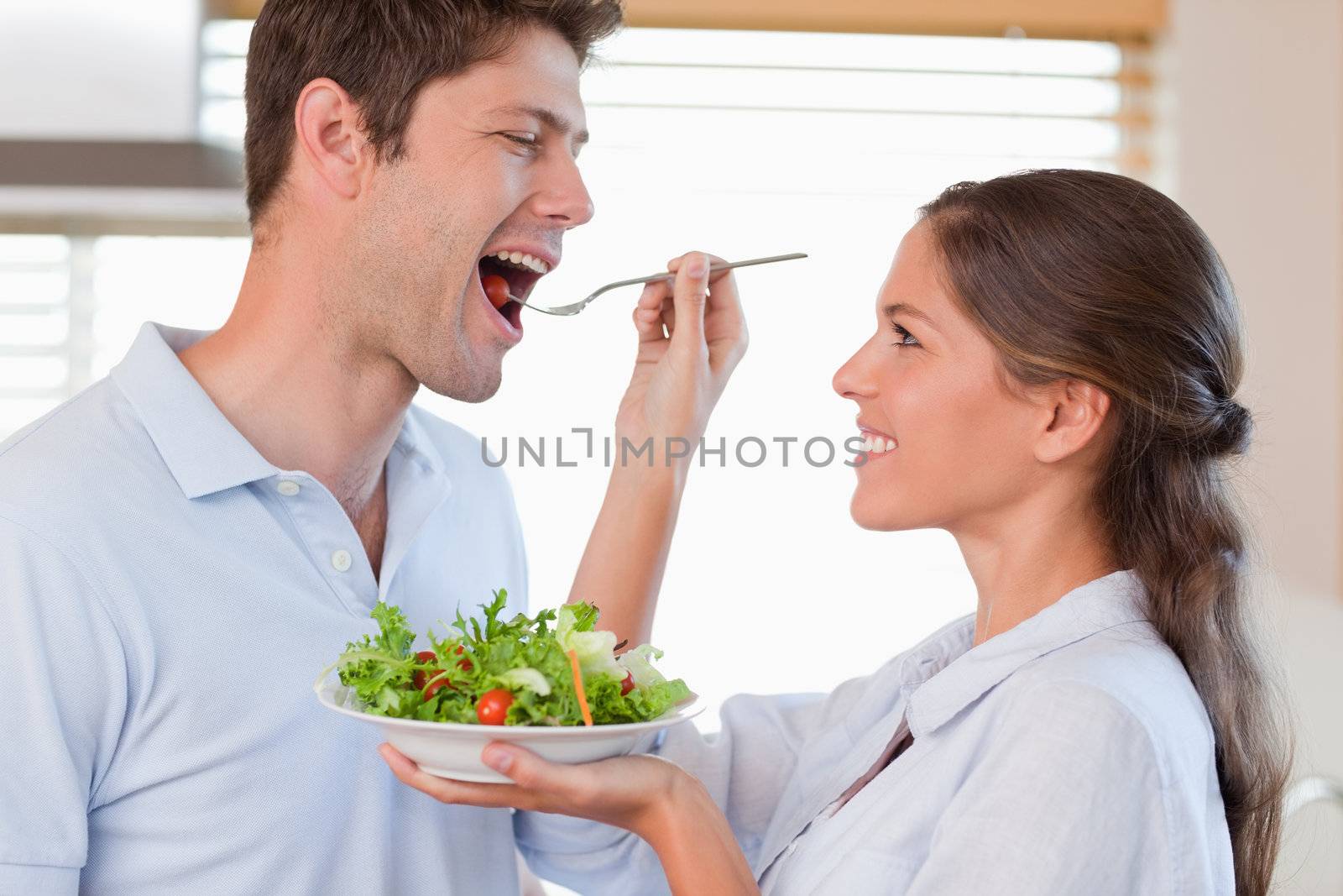 Accomplice couple tasting a salad in their kitchen