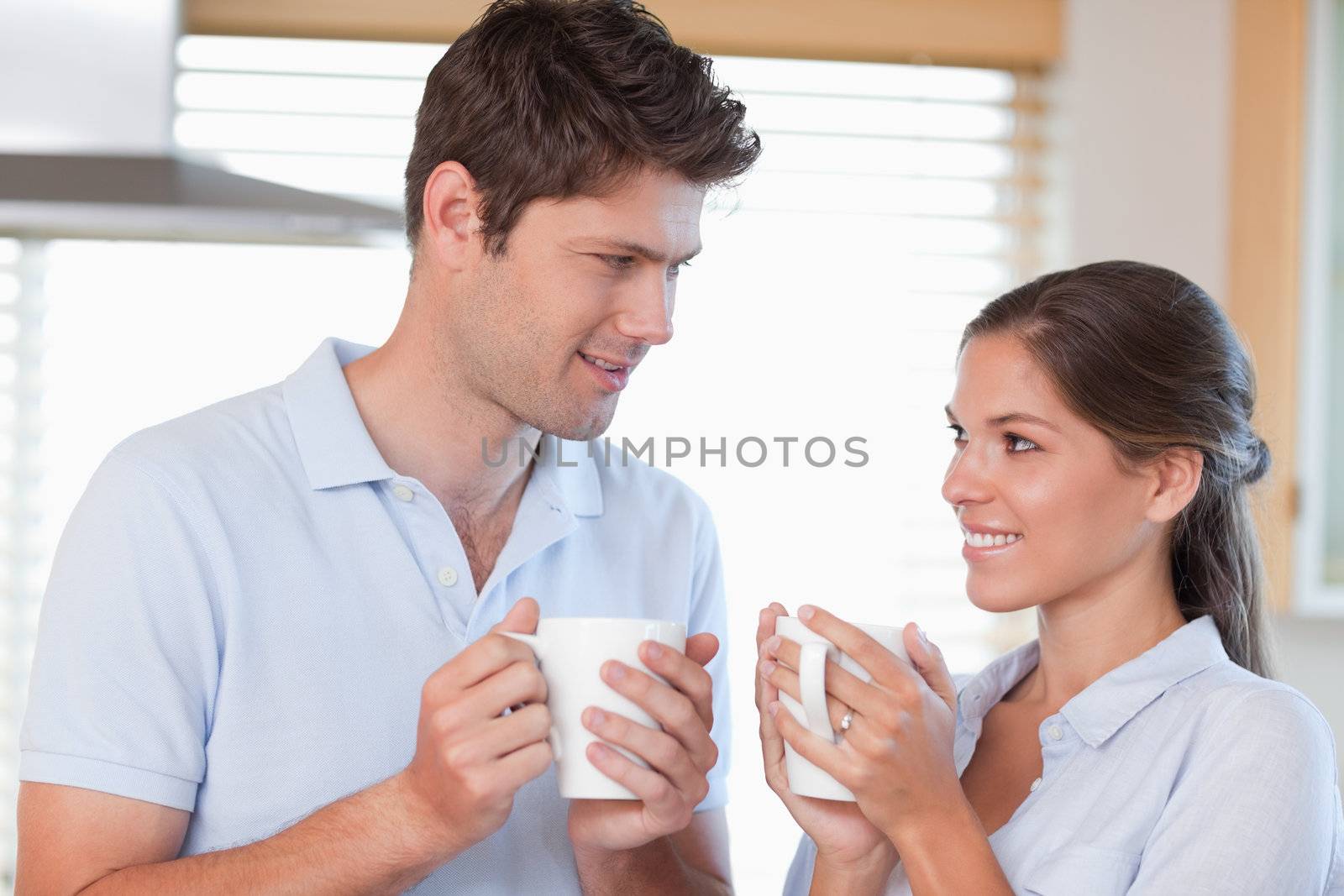 Happy couple drinking tea while looking at each other