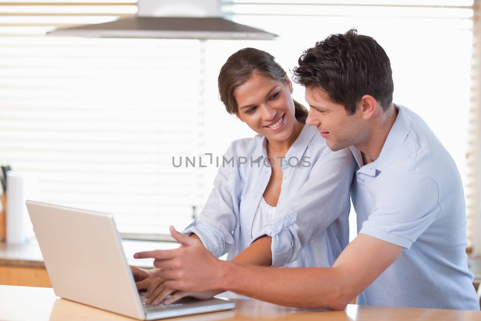 Happy couple using a laptop in their kitchen