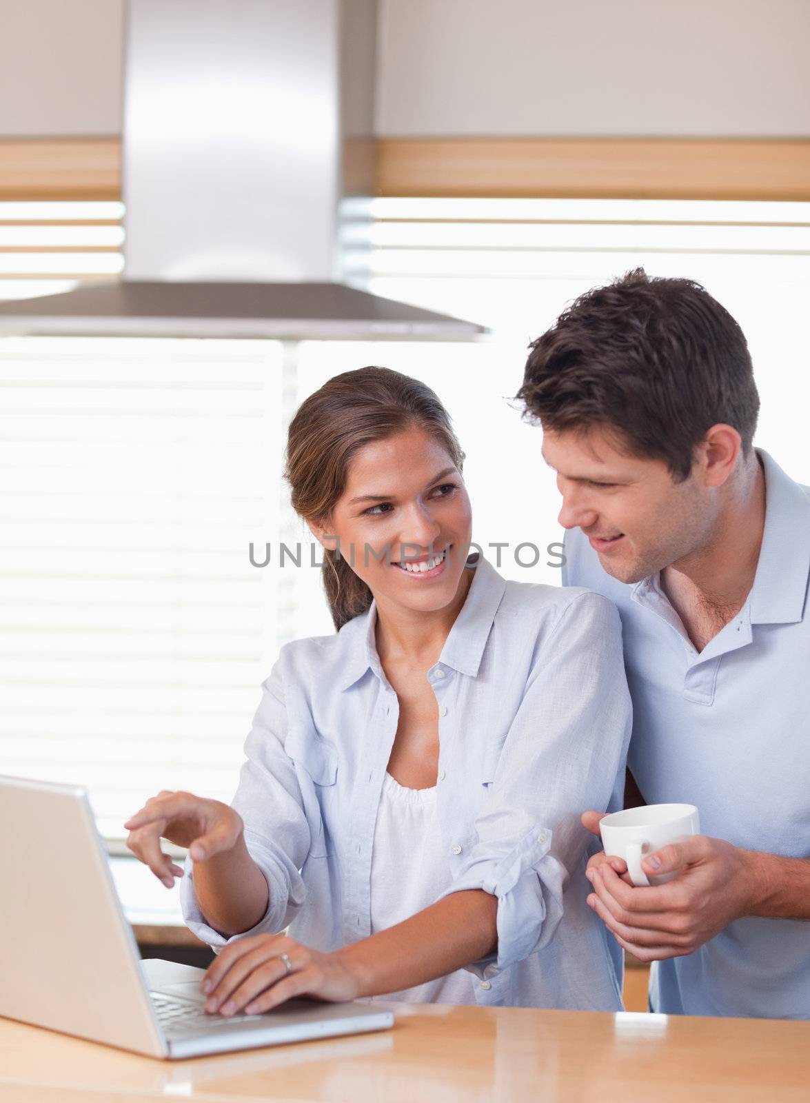 Portrait of a couple using a laptop while having tea in their kitchen