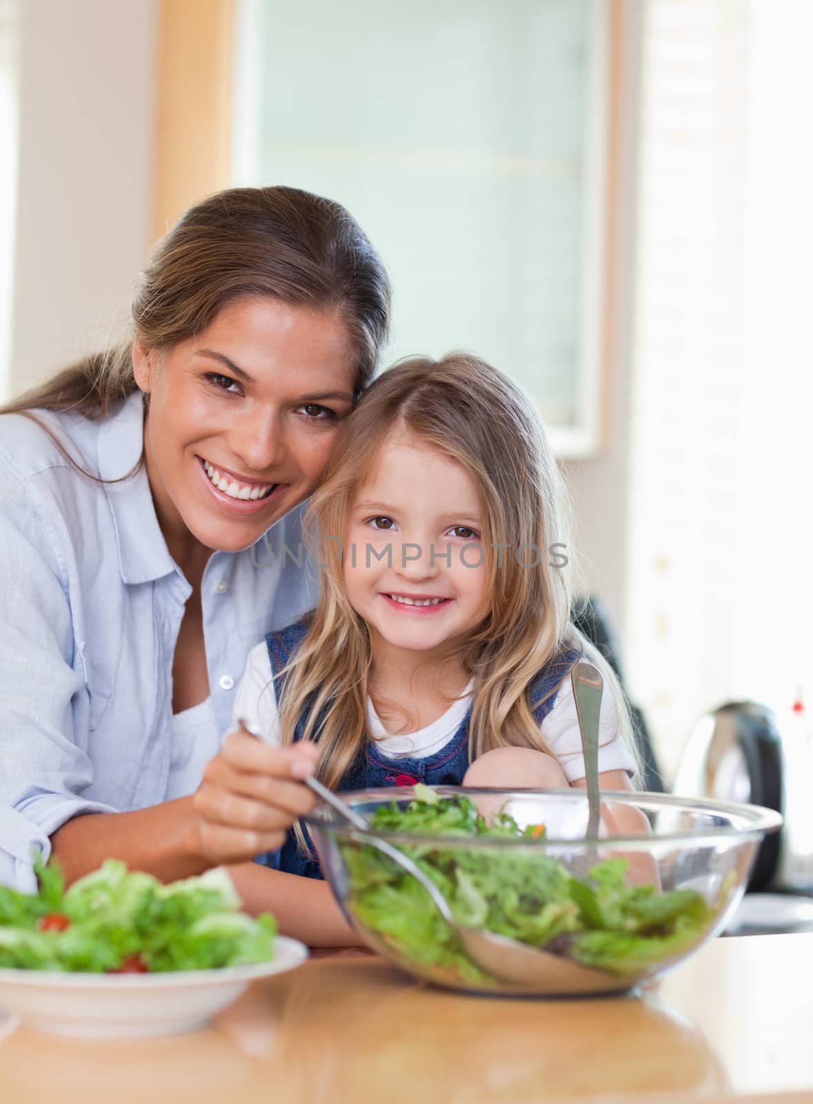 Portrait of a mother and her daughter preparing a salad in their kitchen