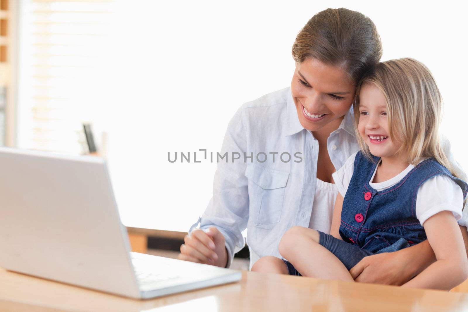 Mother and her daughter using a laptop in their kitchen