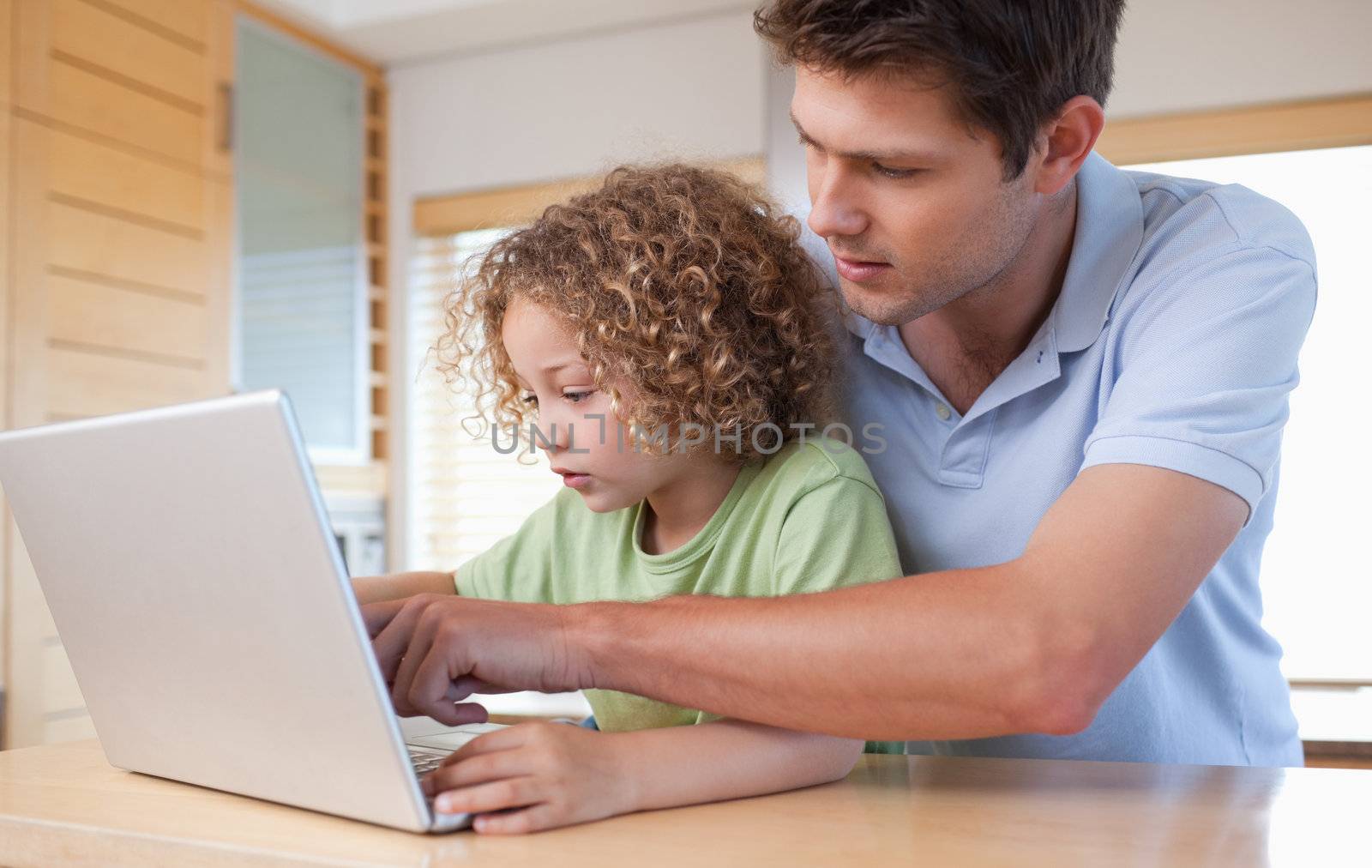 Boy and his father using a laptop in a kitchen