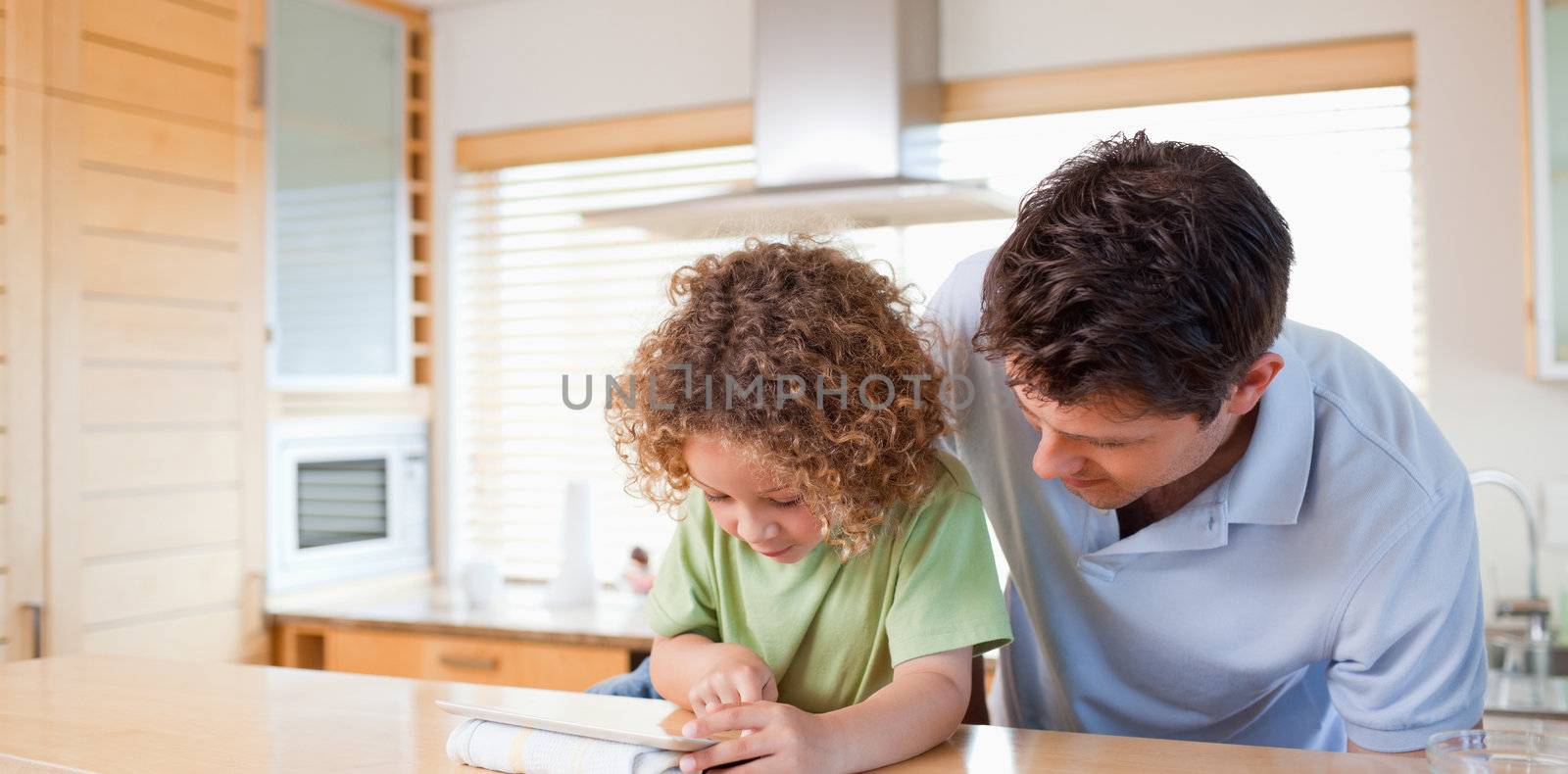 Boy and his father using a tablet computer in their kitchen
