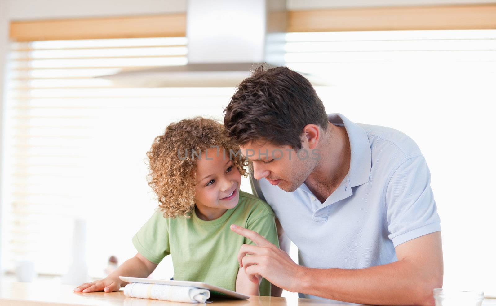 Young boy and his father using a tablet computer in their kitchen