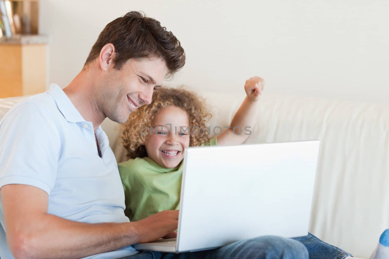 Cheerful boy and his father using a laptop in their living room