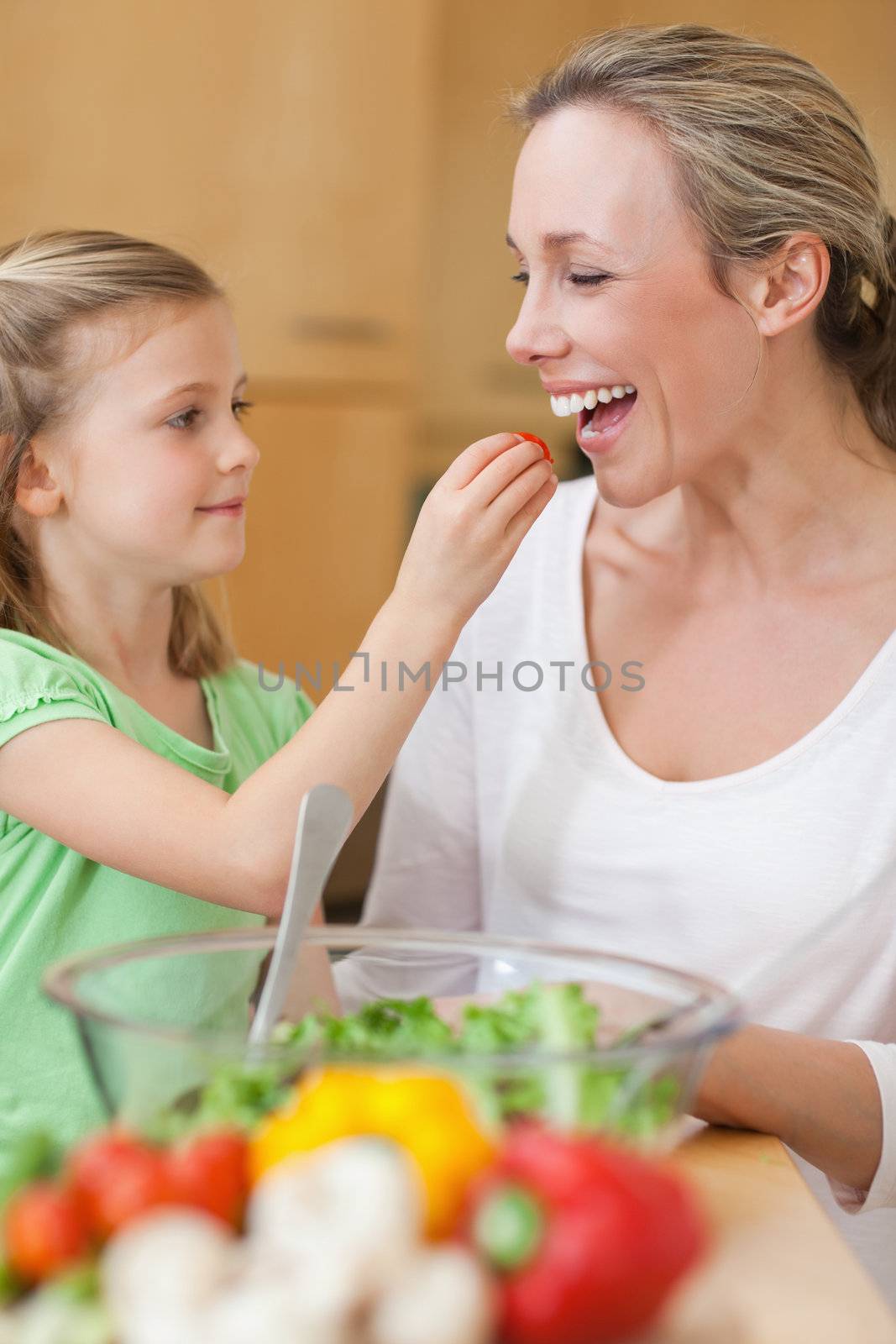 Little girl feeding her mother with salad