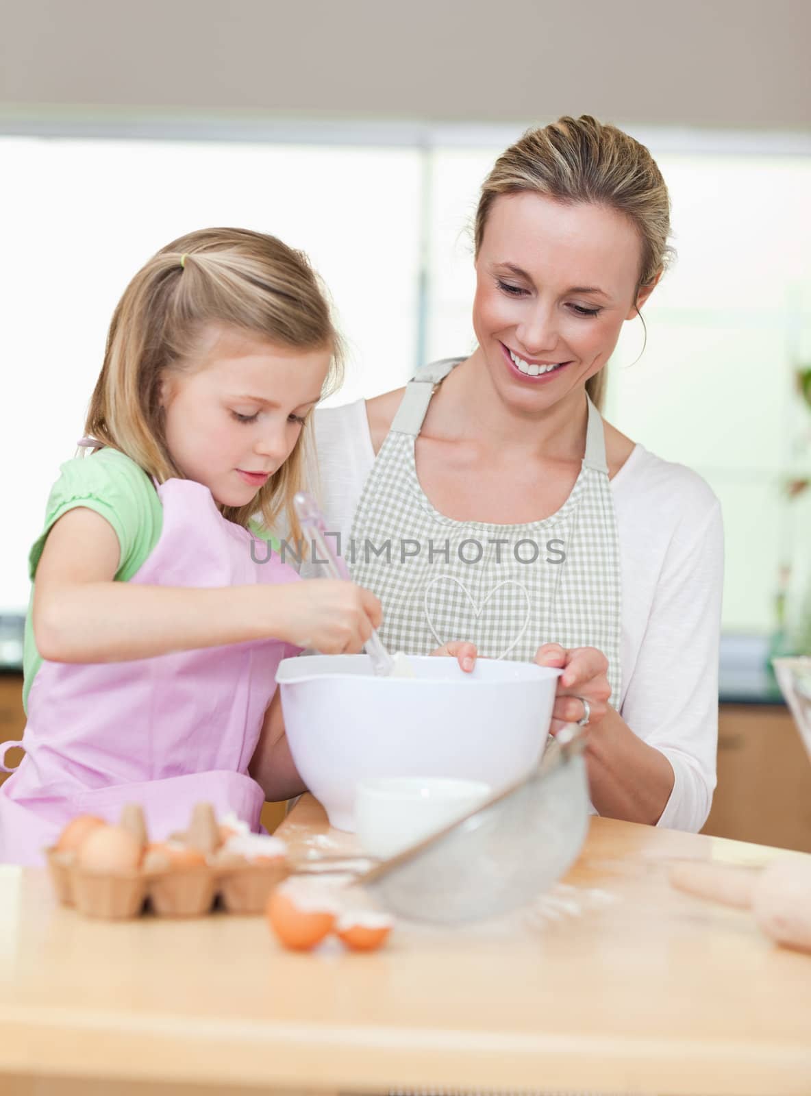Smiling mother and daughter preparing dough for cookies togehter