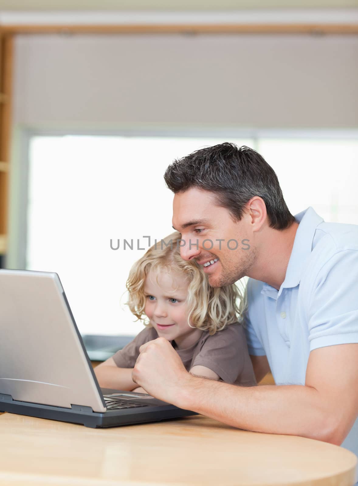 Smiling father and son using laptop together