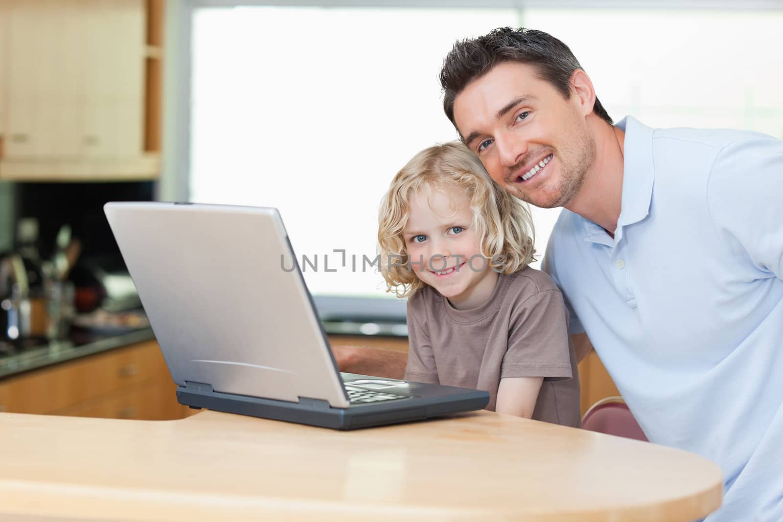 Father and son together with notebook in the kitchen
