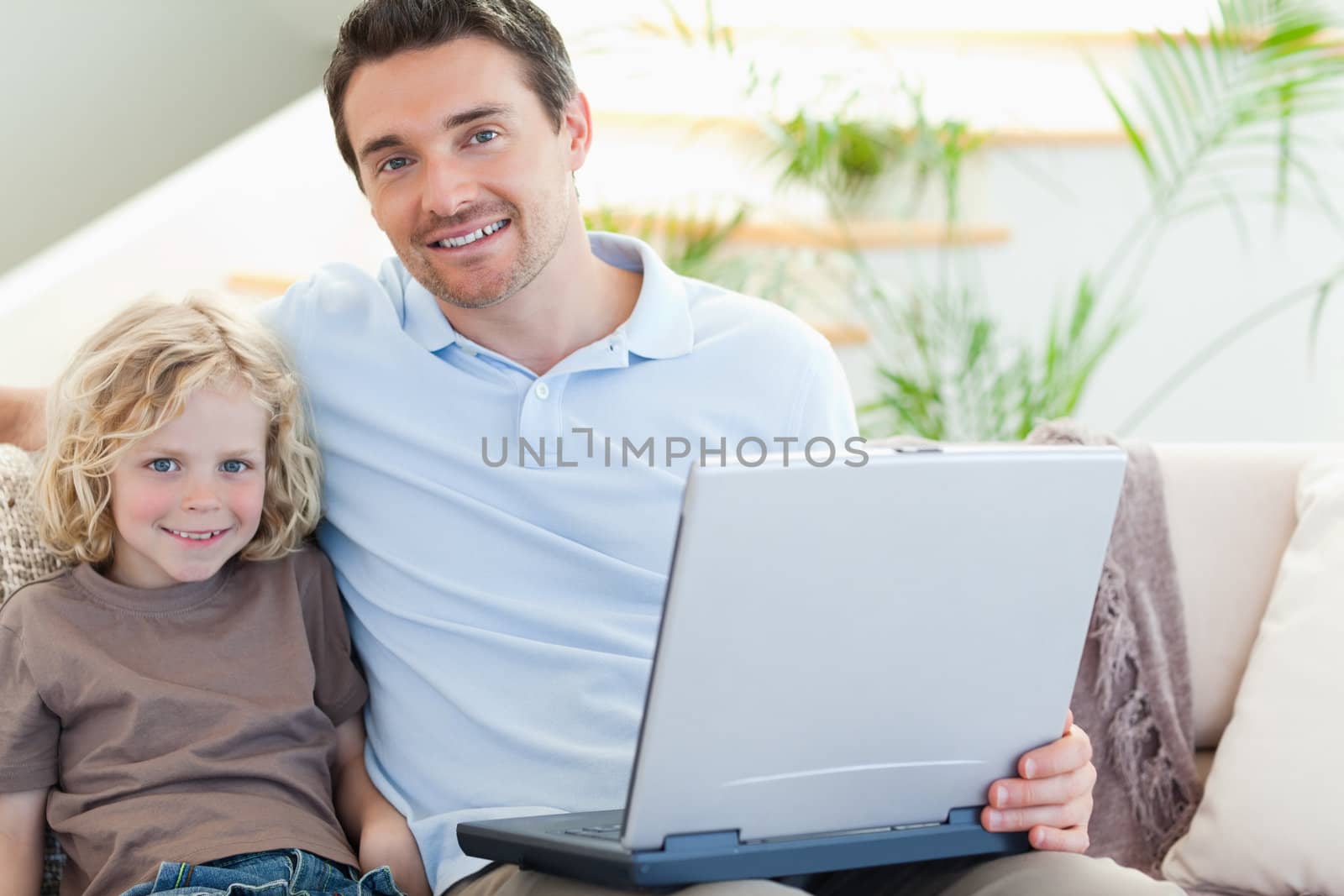 Father and son together on couch with laptop
