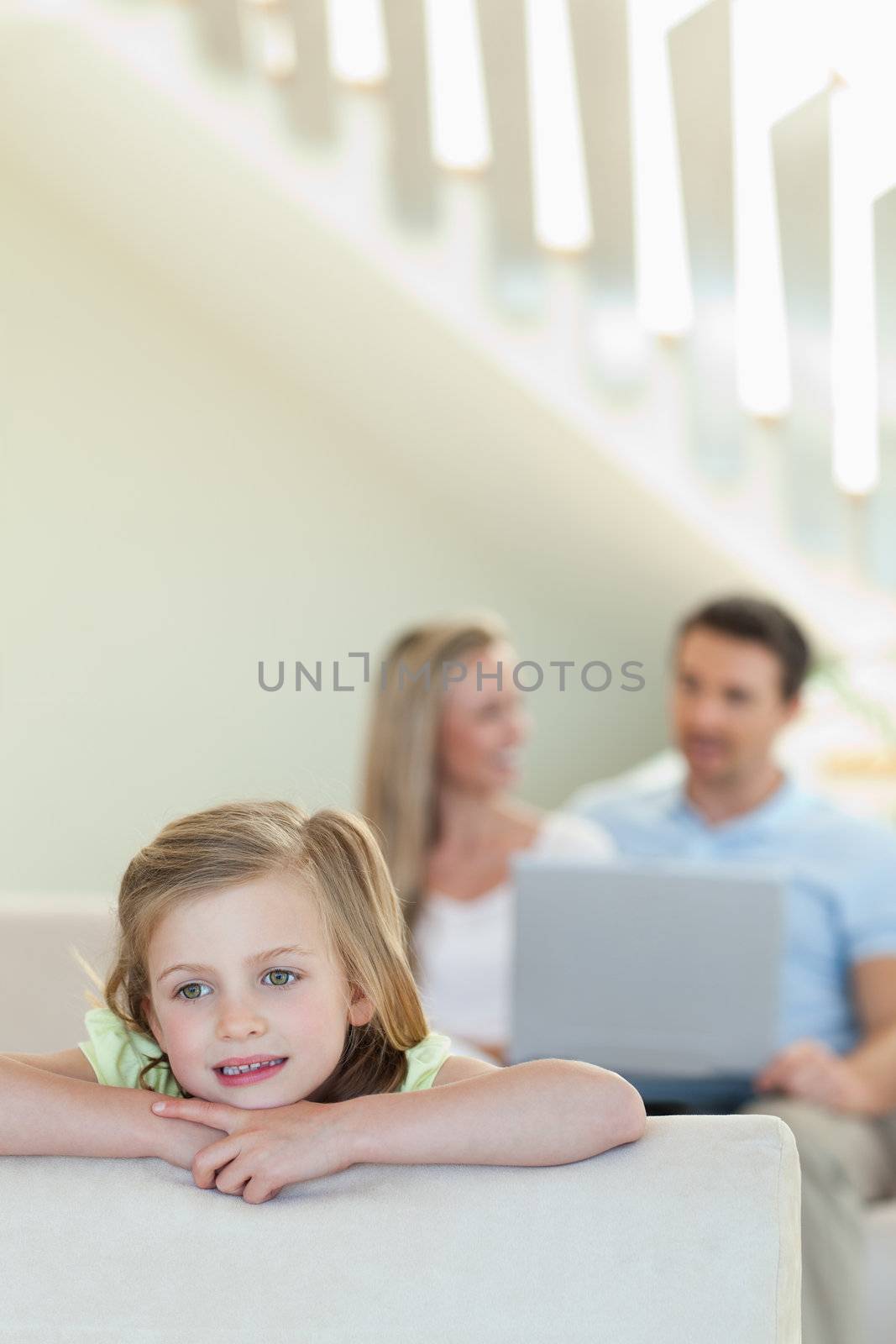 Girl in thoughts with parents behind her by Wavebreakmedia