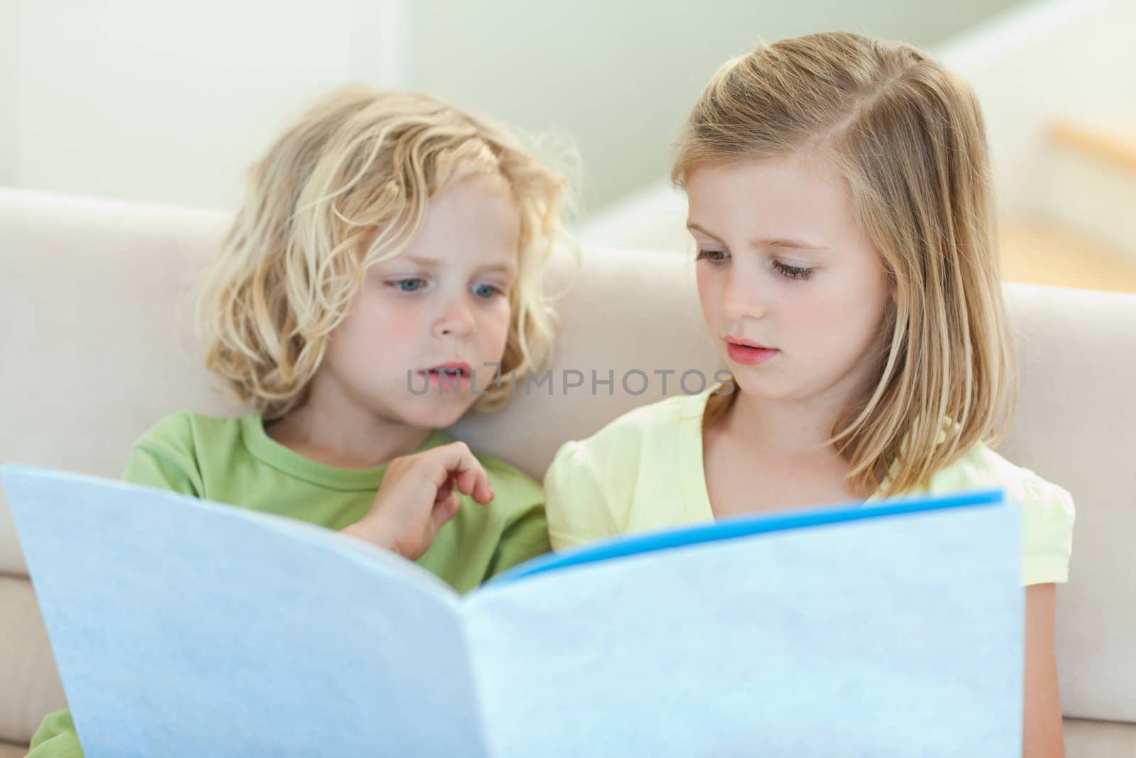 Siblings reading magazine together on the couch