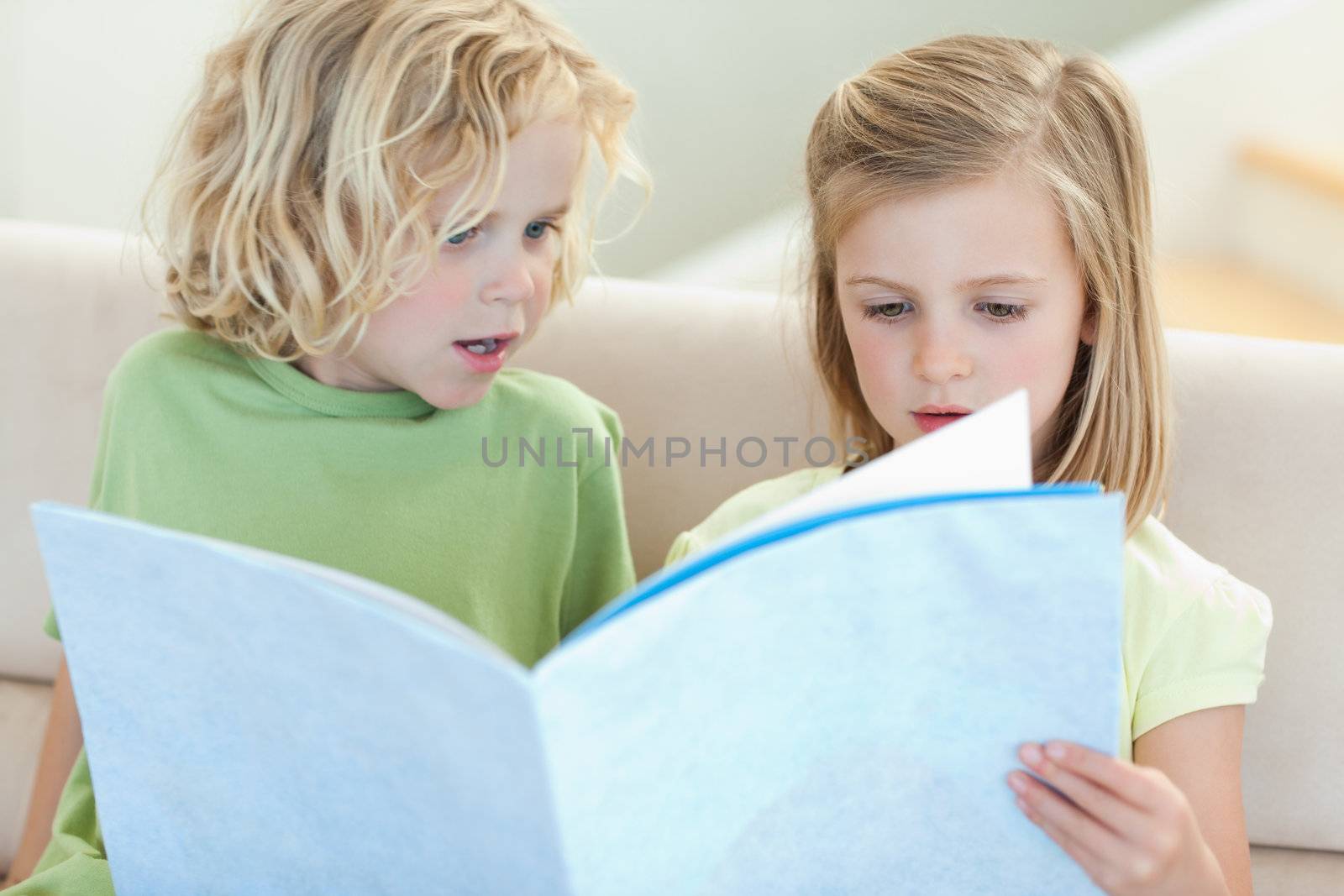 Siblings on the sofa reading magazine together