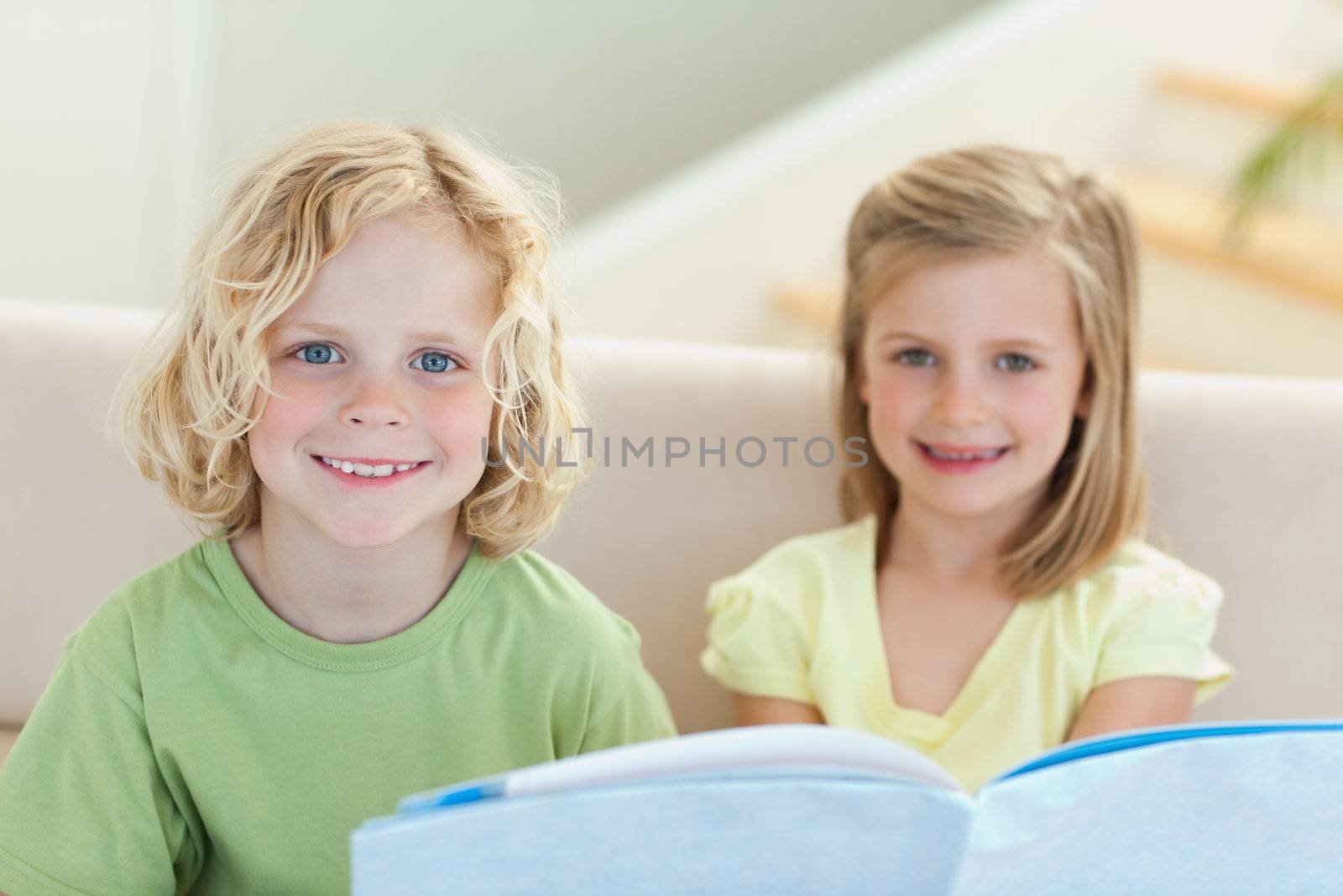 Siblings reading booklet together on the sofa