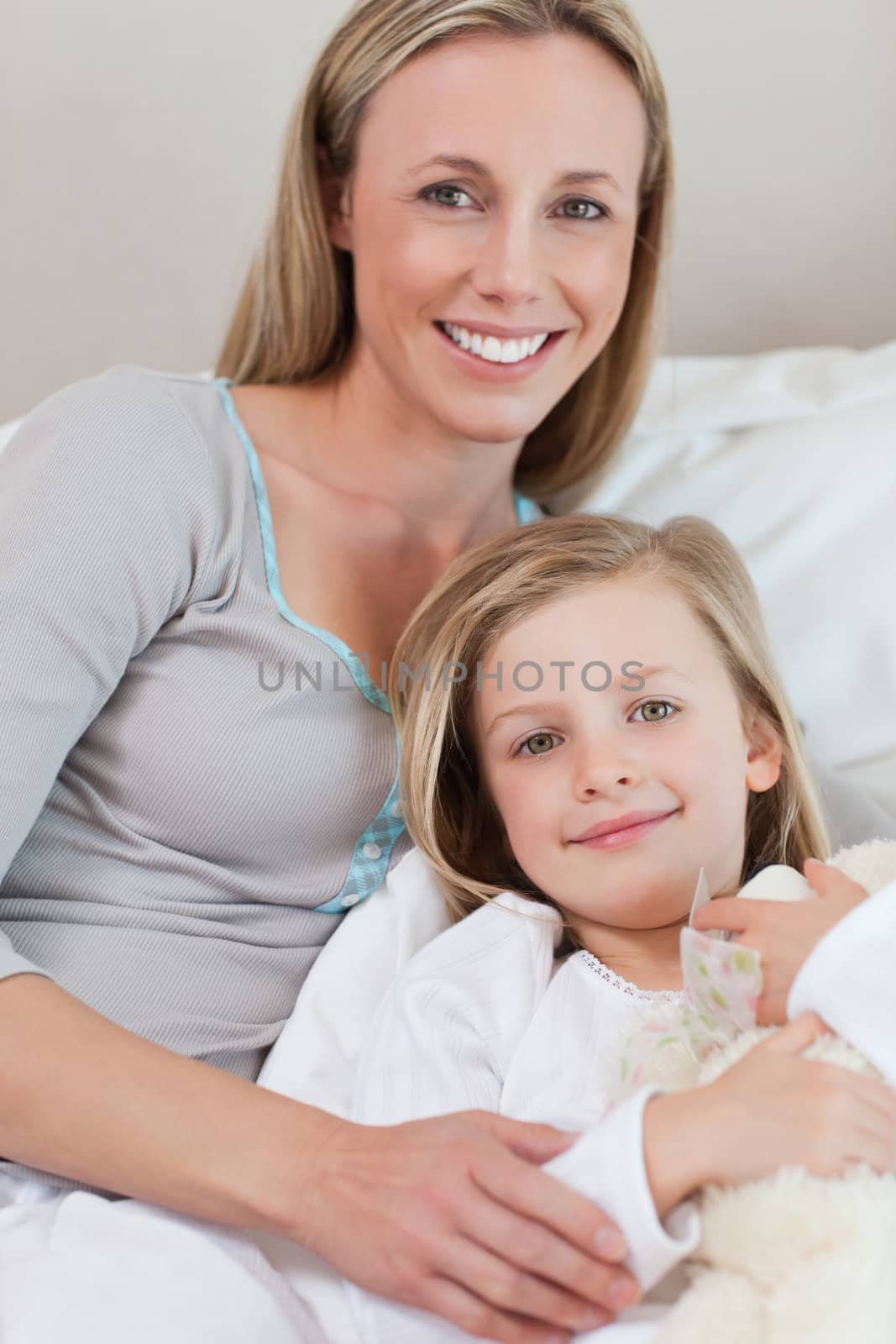 Smiling mother holding her daughter on the bed