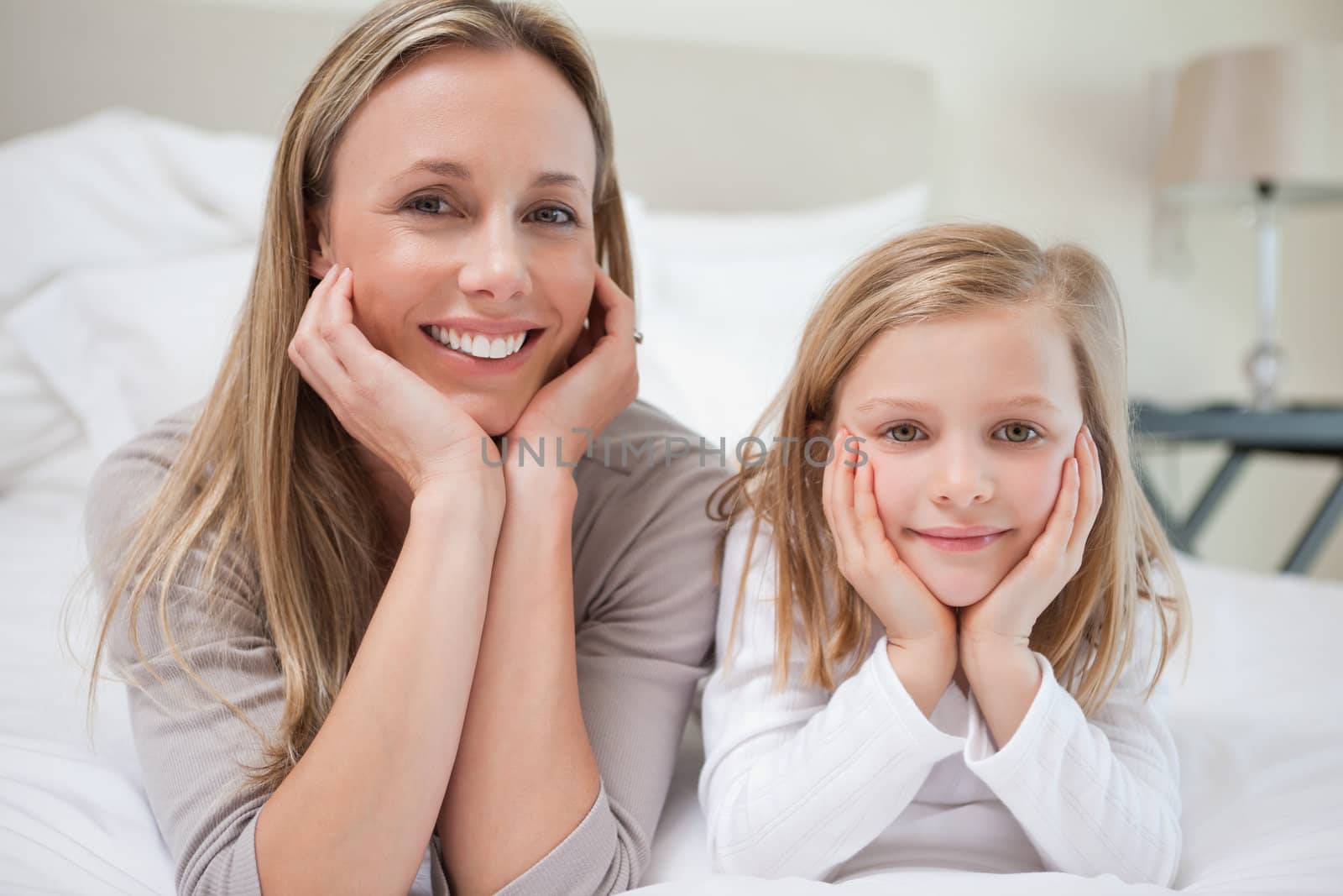 Smiling mother and daughter lying on the bed together