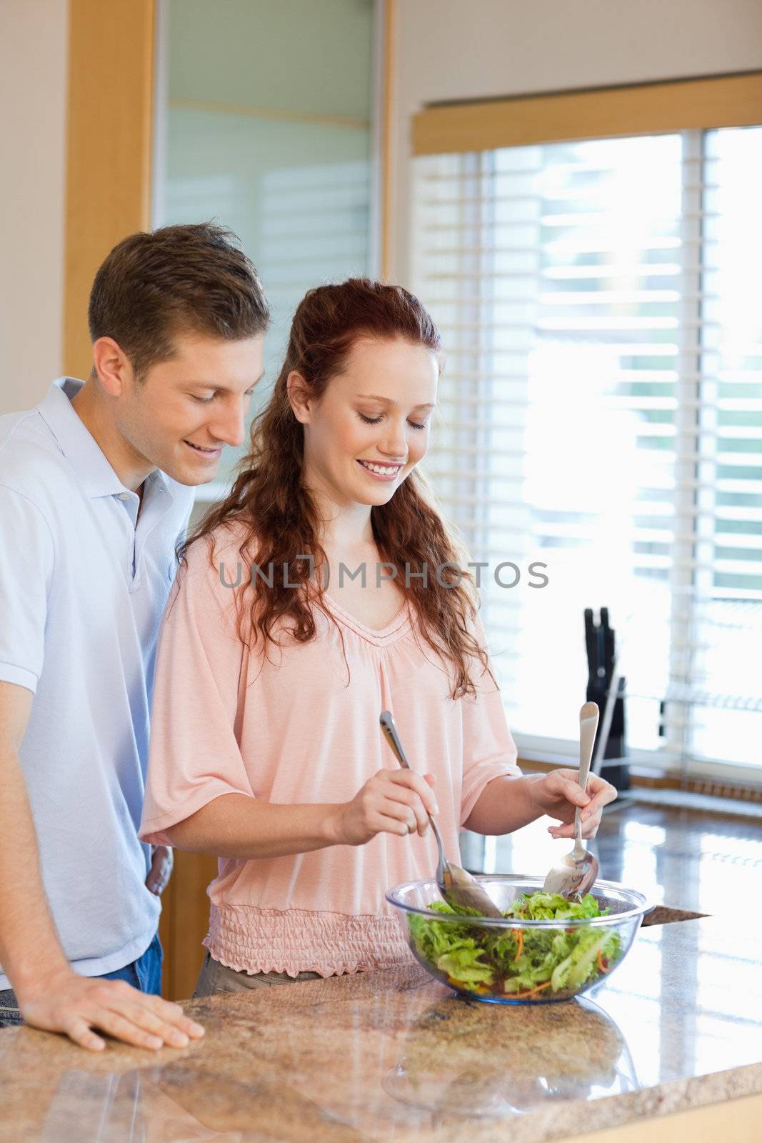Young man having a look at his girlfriends salad